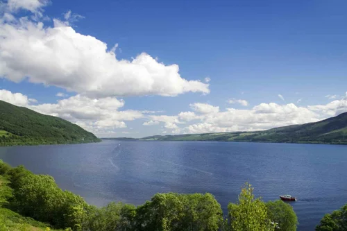 Loch Ness stretching between green hills under a blue sky