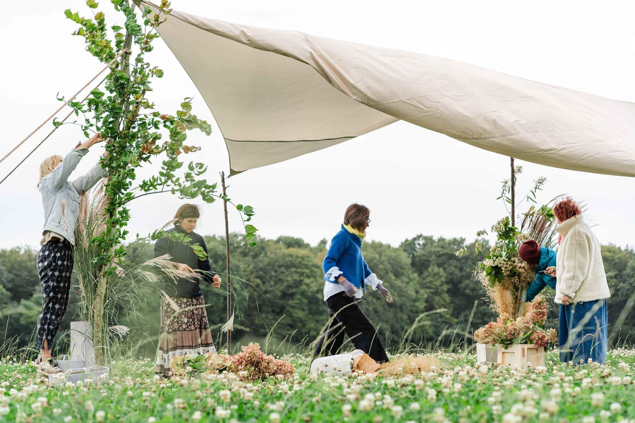 florists at a table in meadow set up for wedding