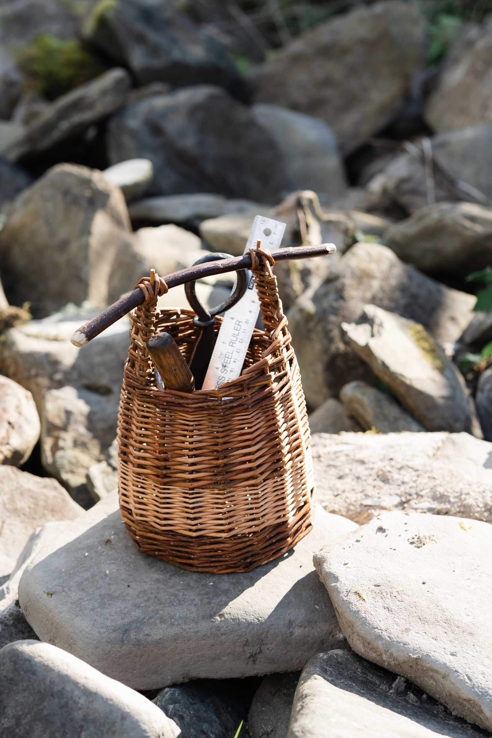 willow basket with tools in on stones outside