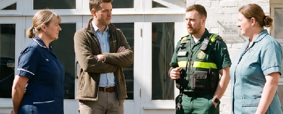 Four people, including a police officer, standing outside and having a conversation.