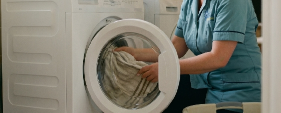 A person loading laundry into a front-loading washing machine.