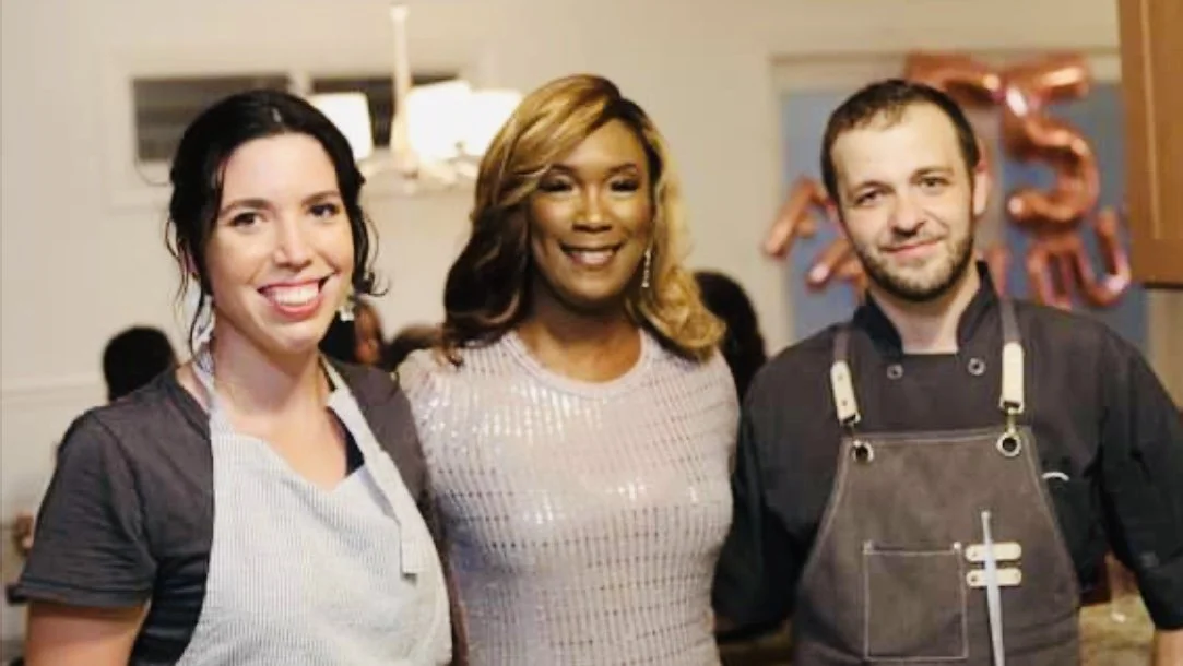 Three people smiling at a celebration with '15' balloons in the background.