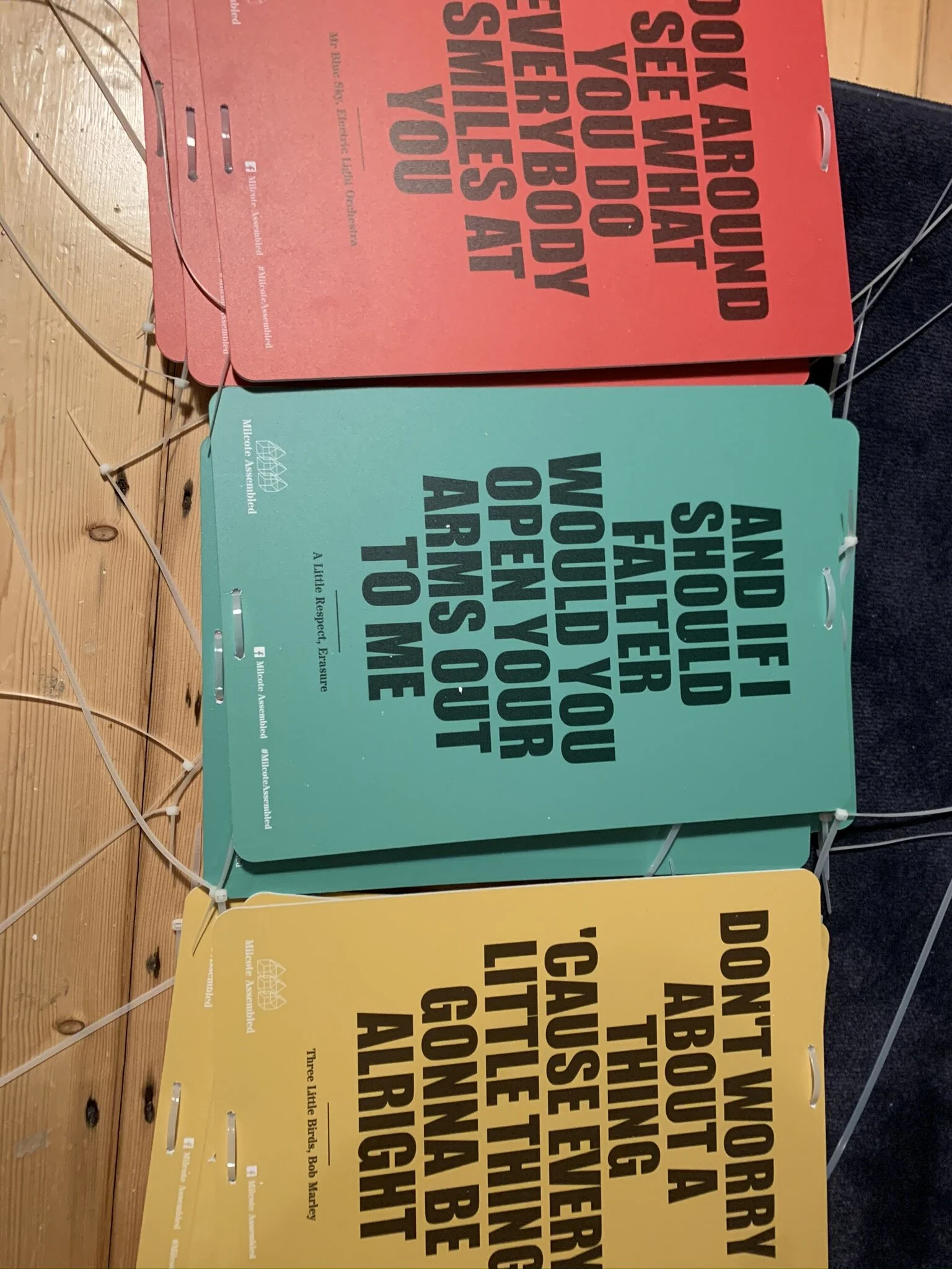 Colorful display boards with large black text on a wooden surface, featuring words such as 'ASK,' 'ABOUT,' 'YOUR,' 'GOT,' 'COMMUNITY,' 'CHILD,' 'TALK,' and other related phrases