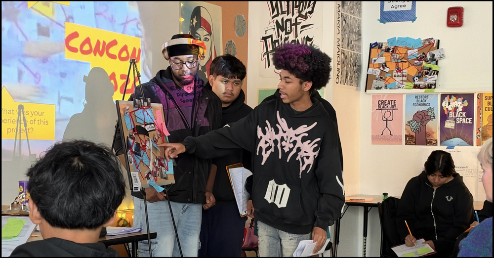 ARISE students talking together in a classroom covered in student art