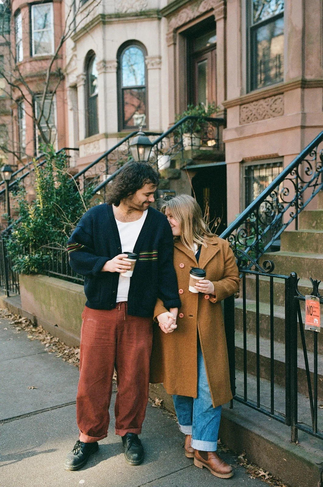 Couple holding hands on a stroll with coffee