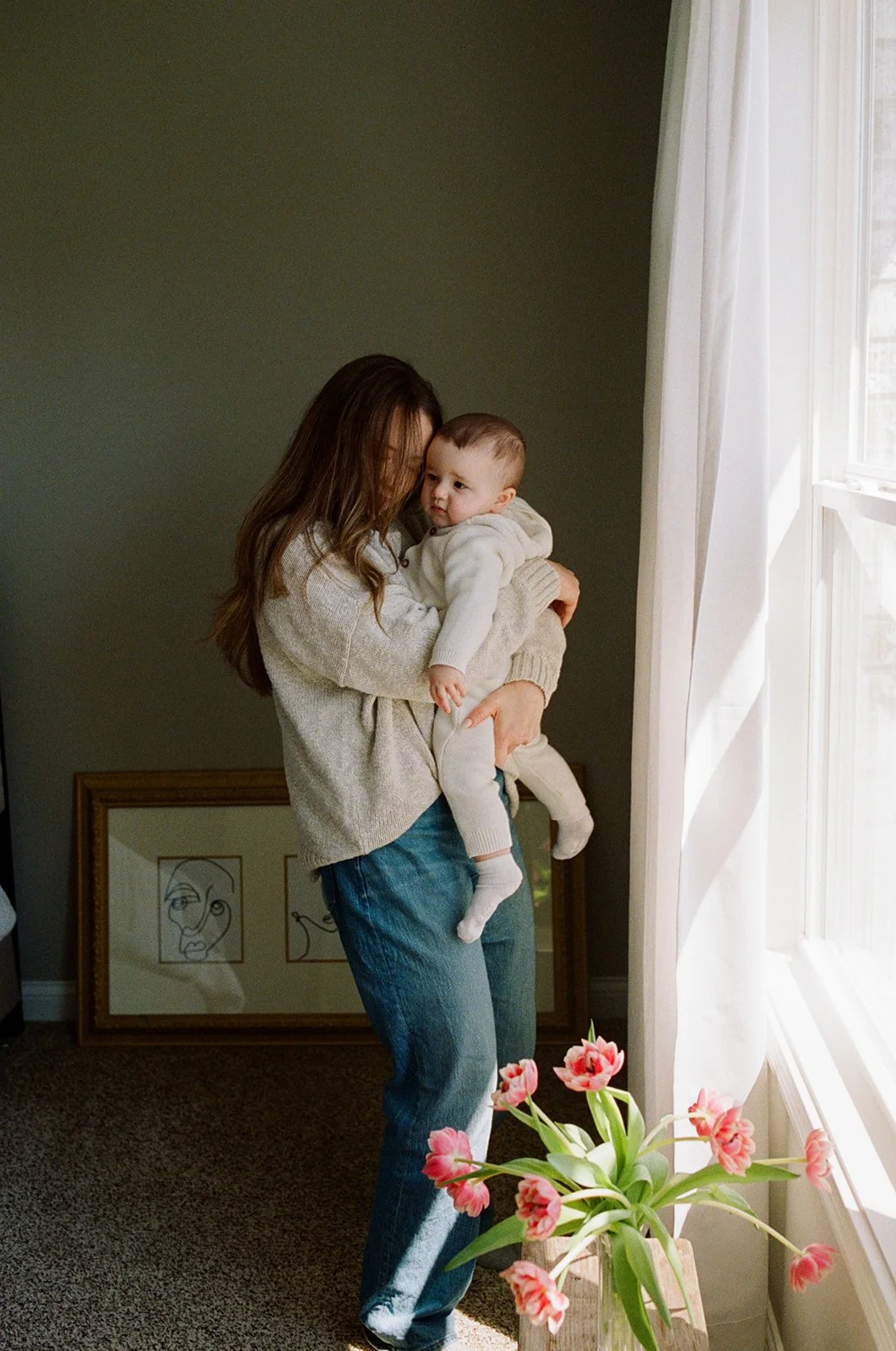 Mom snuggling a young child in their home