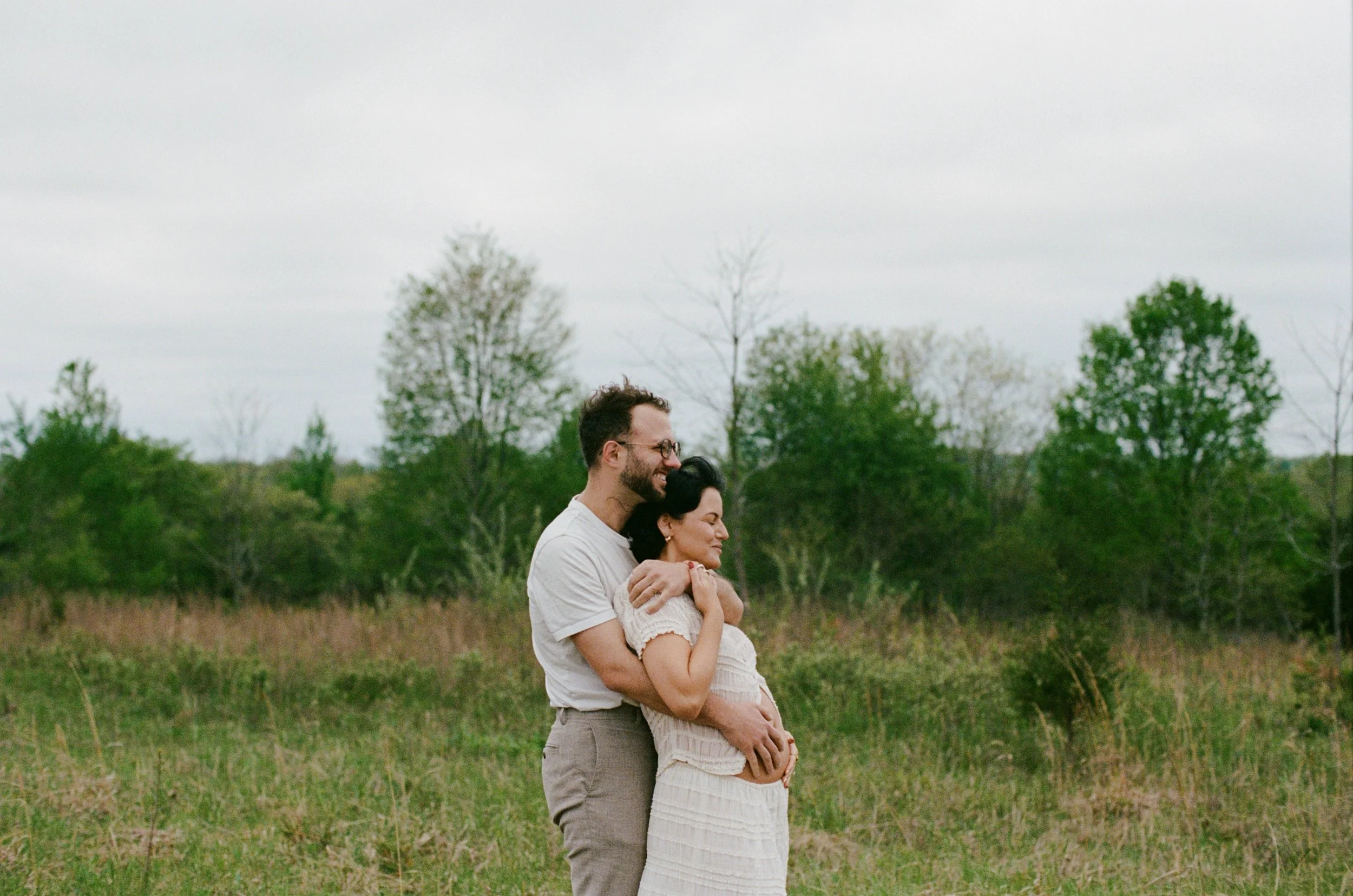 Couple in nature, posing to show off their baby belly with love