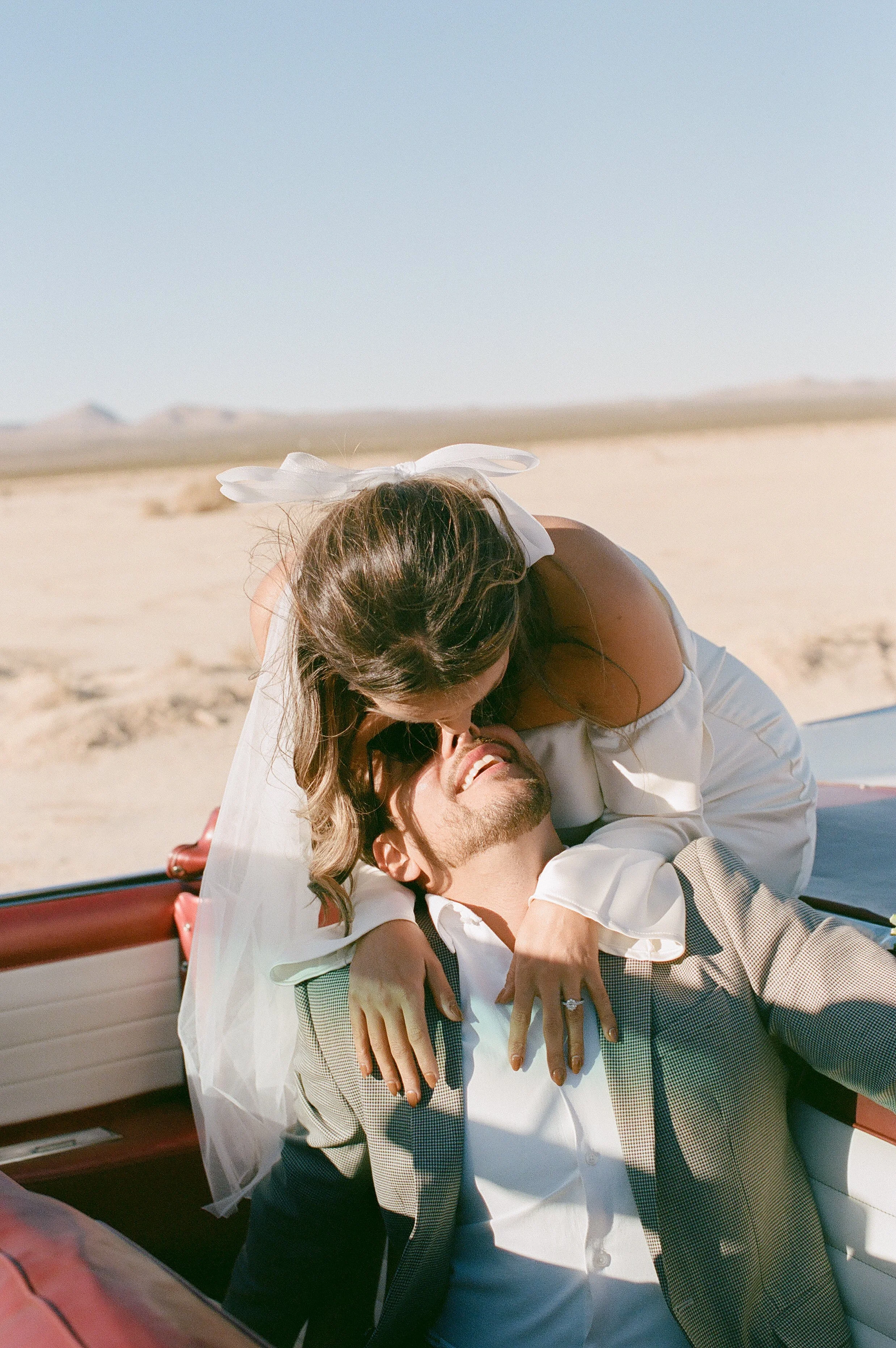 Whimsical shot of the Bride and Groom sitting in a vintage convertible