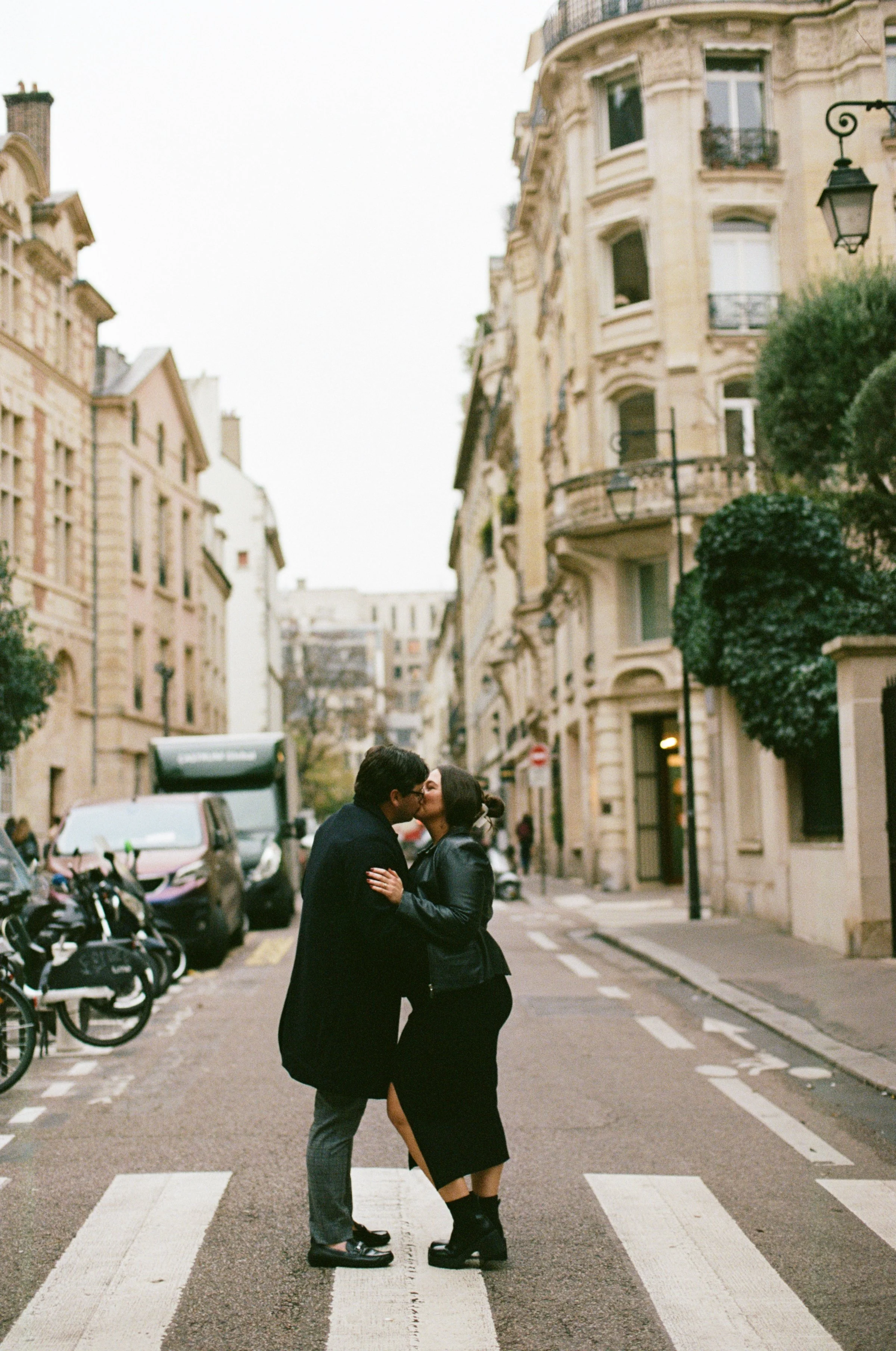 Couple standing together in the middle of a cross walk kissing