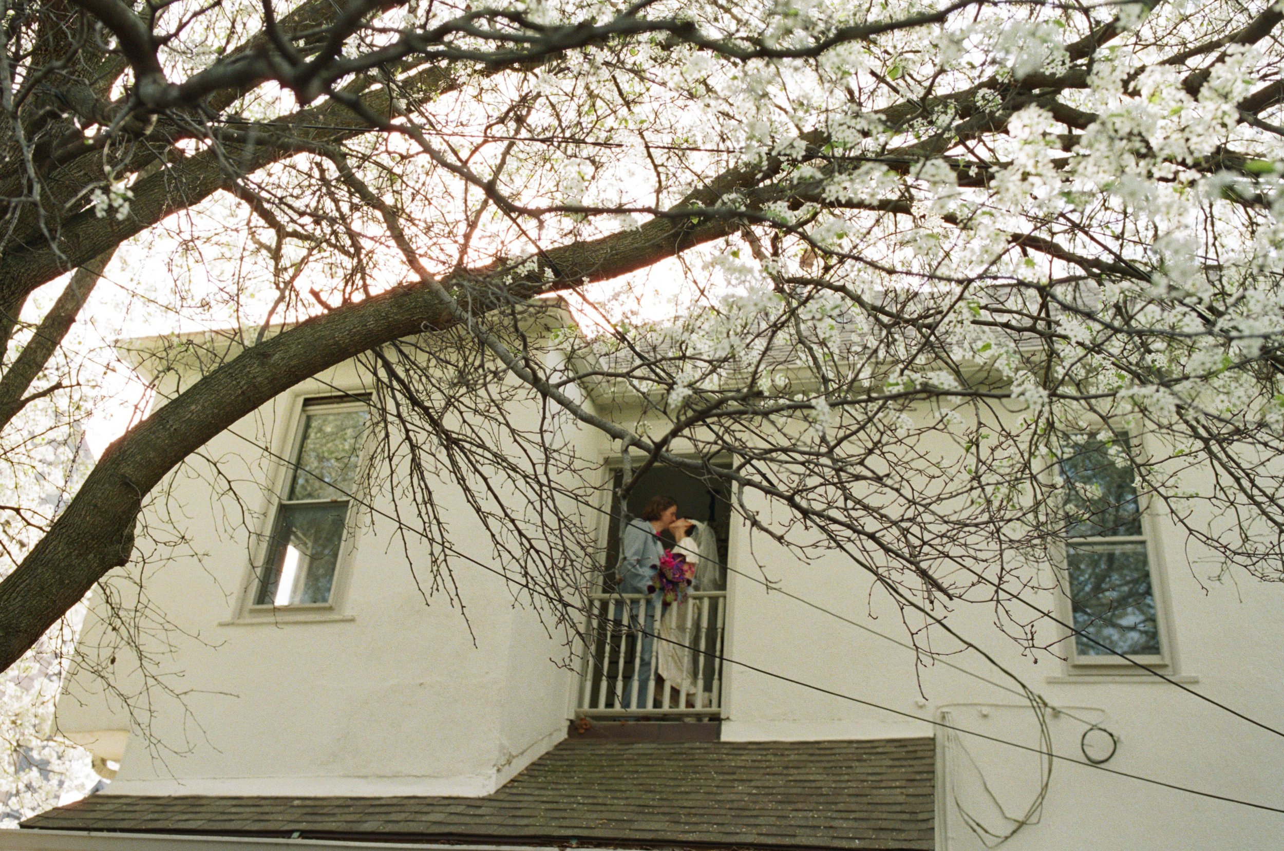 Distance shot of a couple kissing on their wedding day while standing on a second story balcony