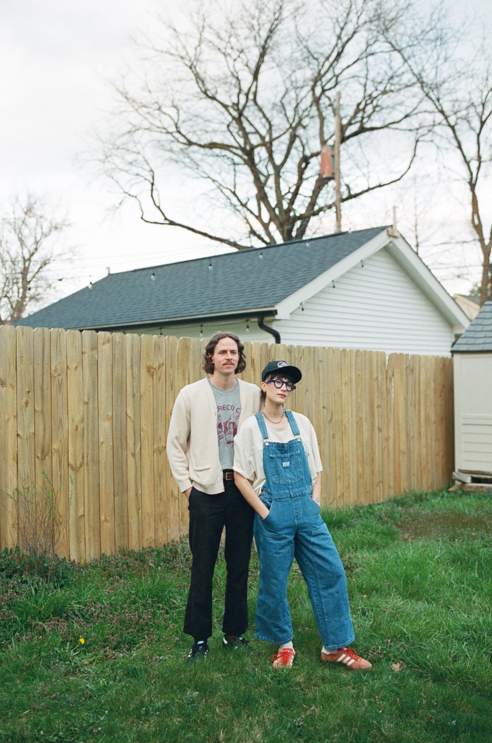 Lifestyle shot of a couple standing together in their yard with a fence behind them