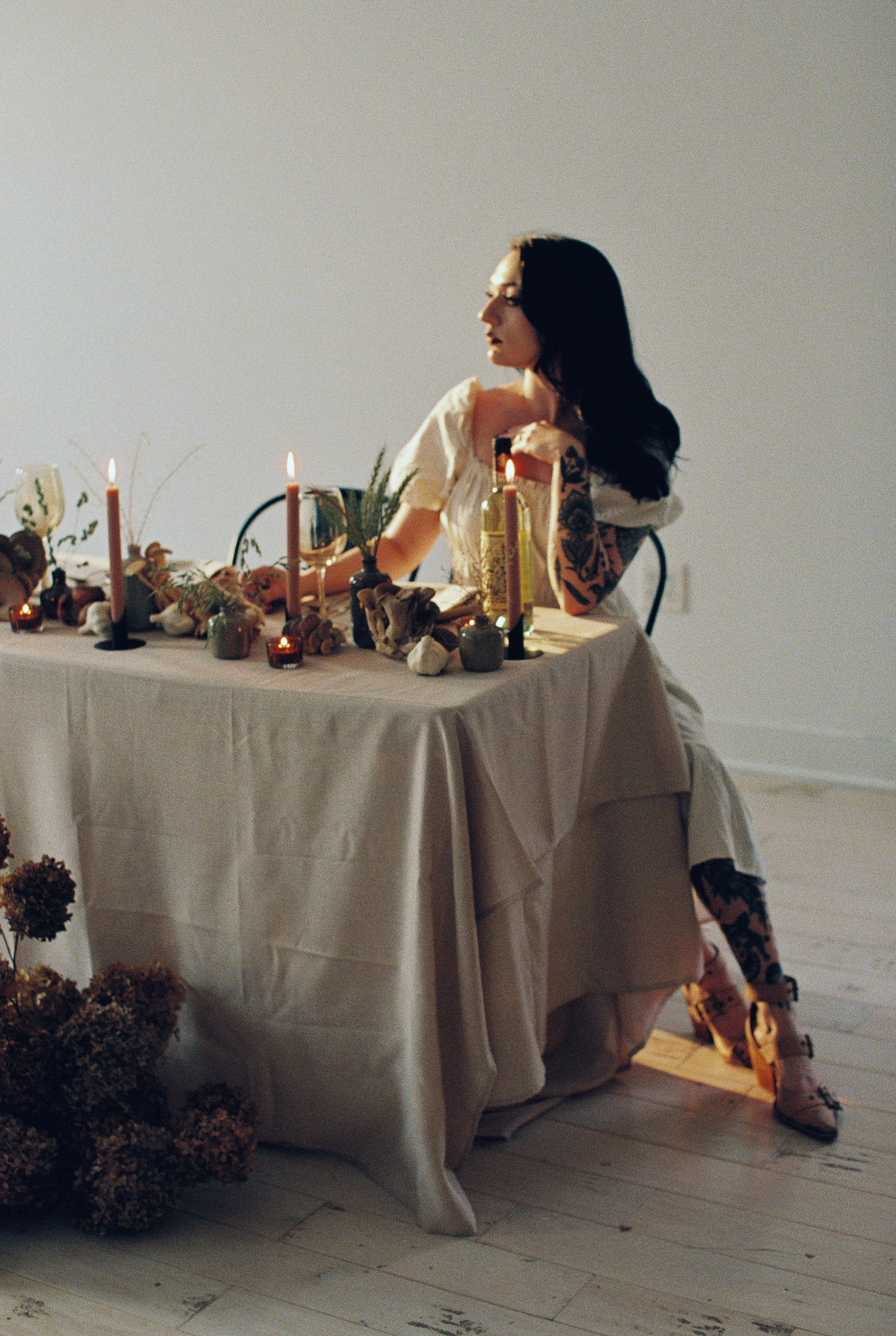 Moody shot of a women sitting at a table with candles and flowers