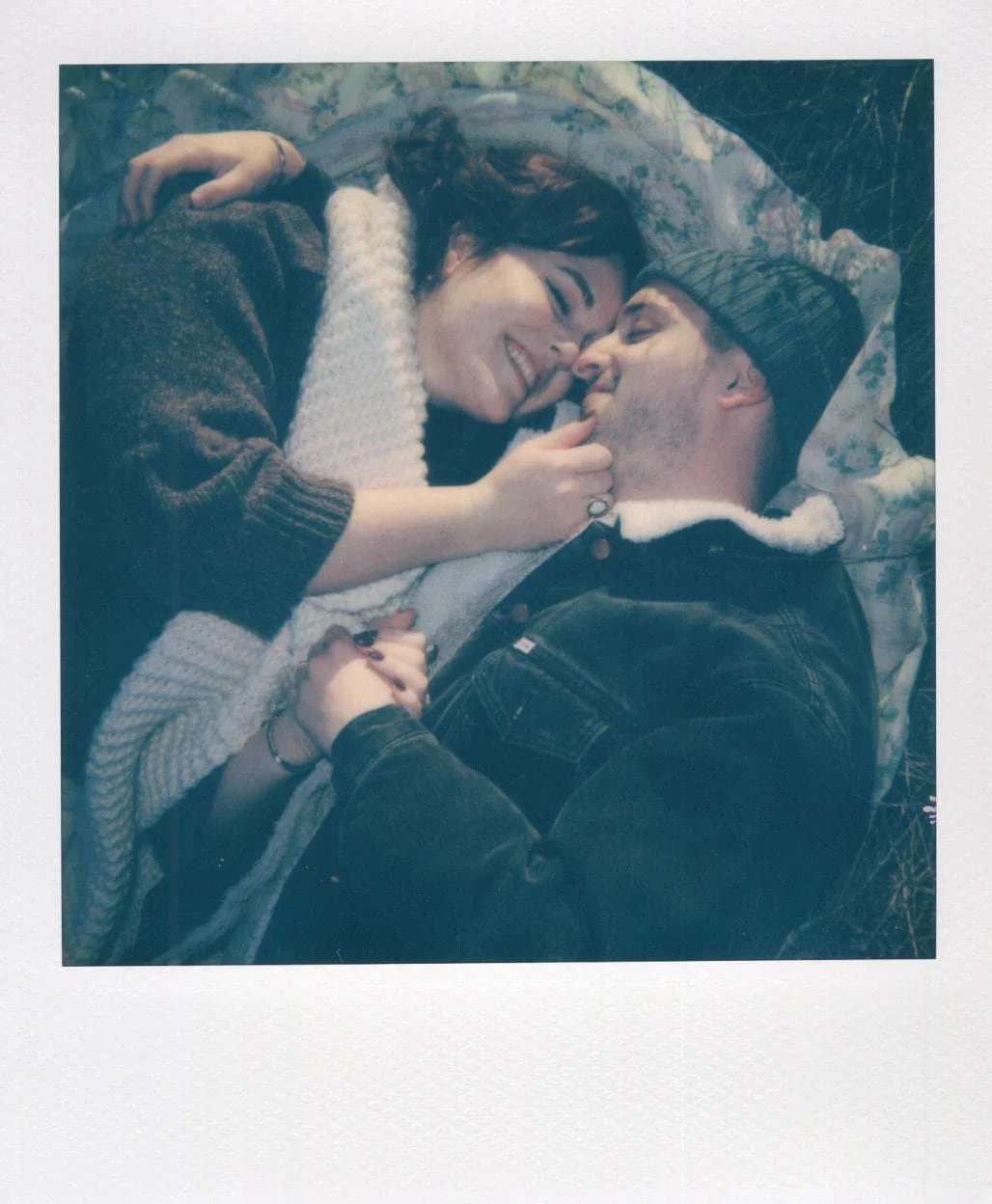 Polaroid of a couple lying on the grass staring into each others eyes