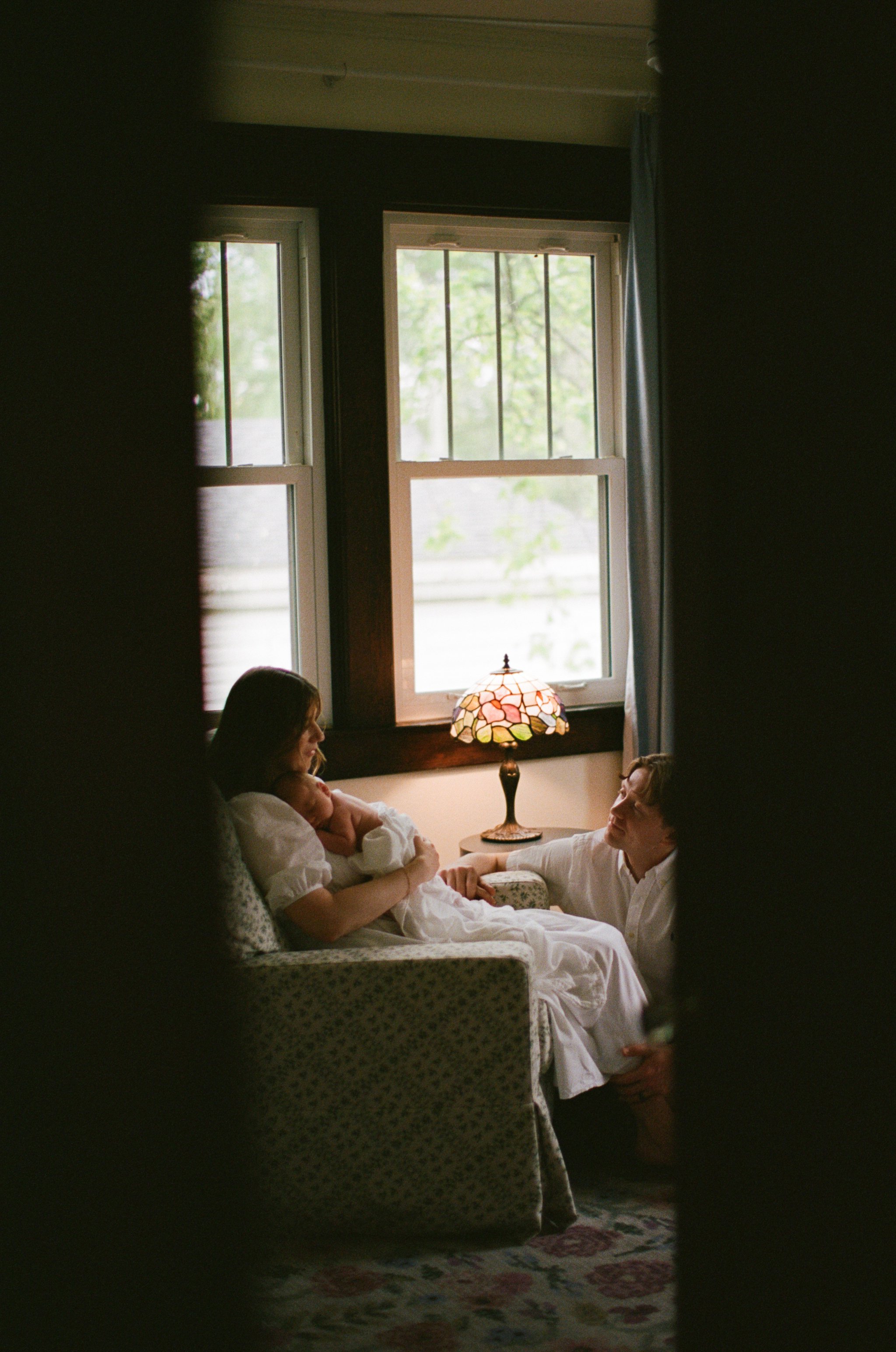 Mom and Dad snuggling a fresh baby in their home