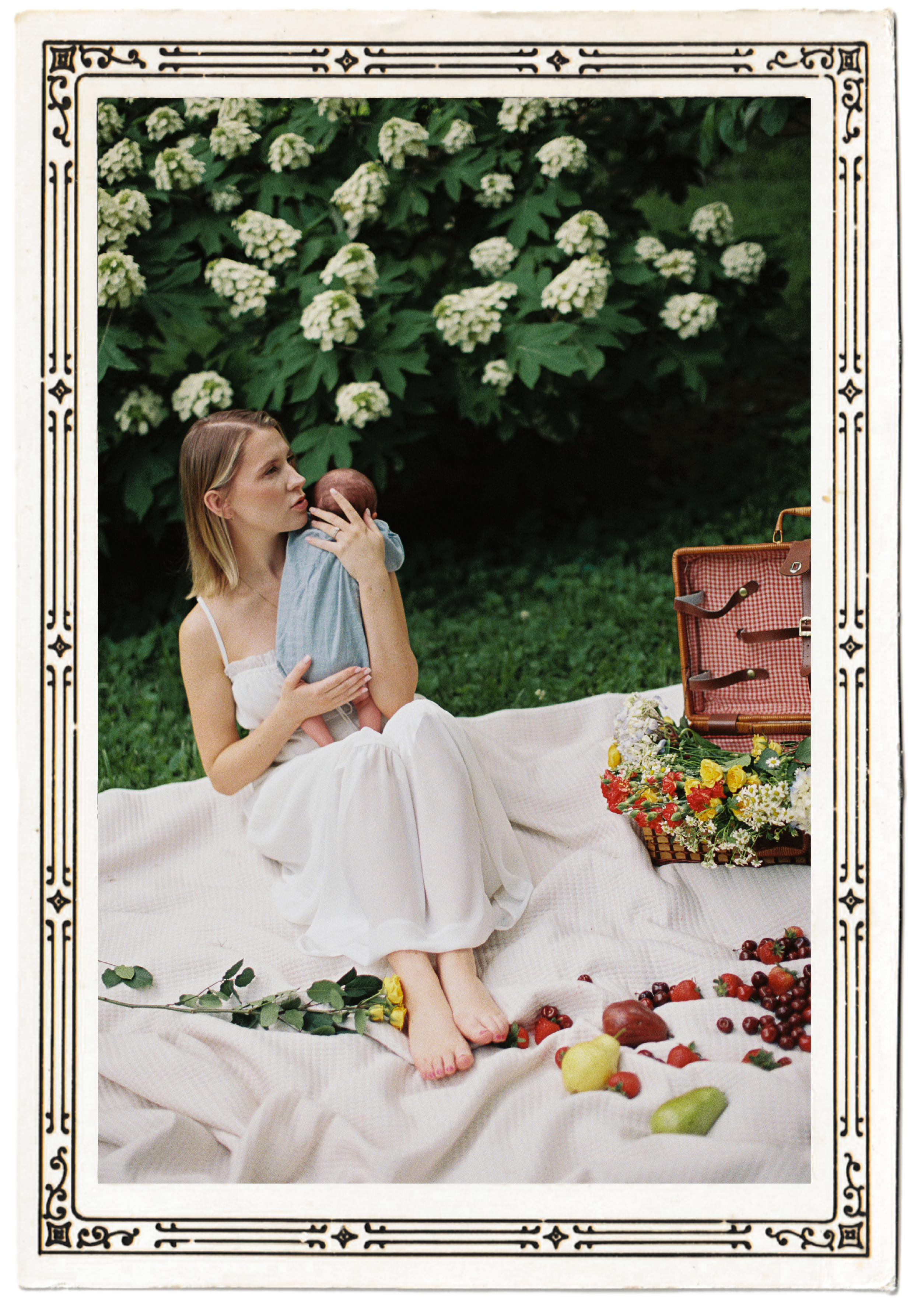Family photo of a mom sitting on a picnic tablecloth holding her young child