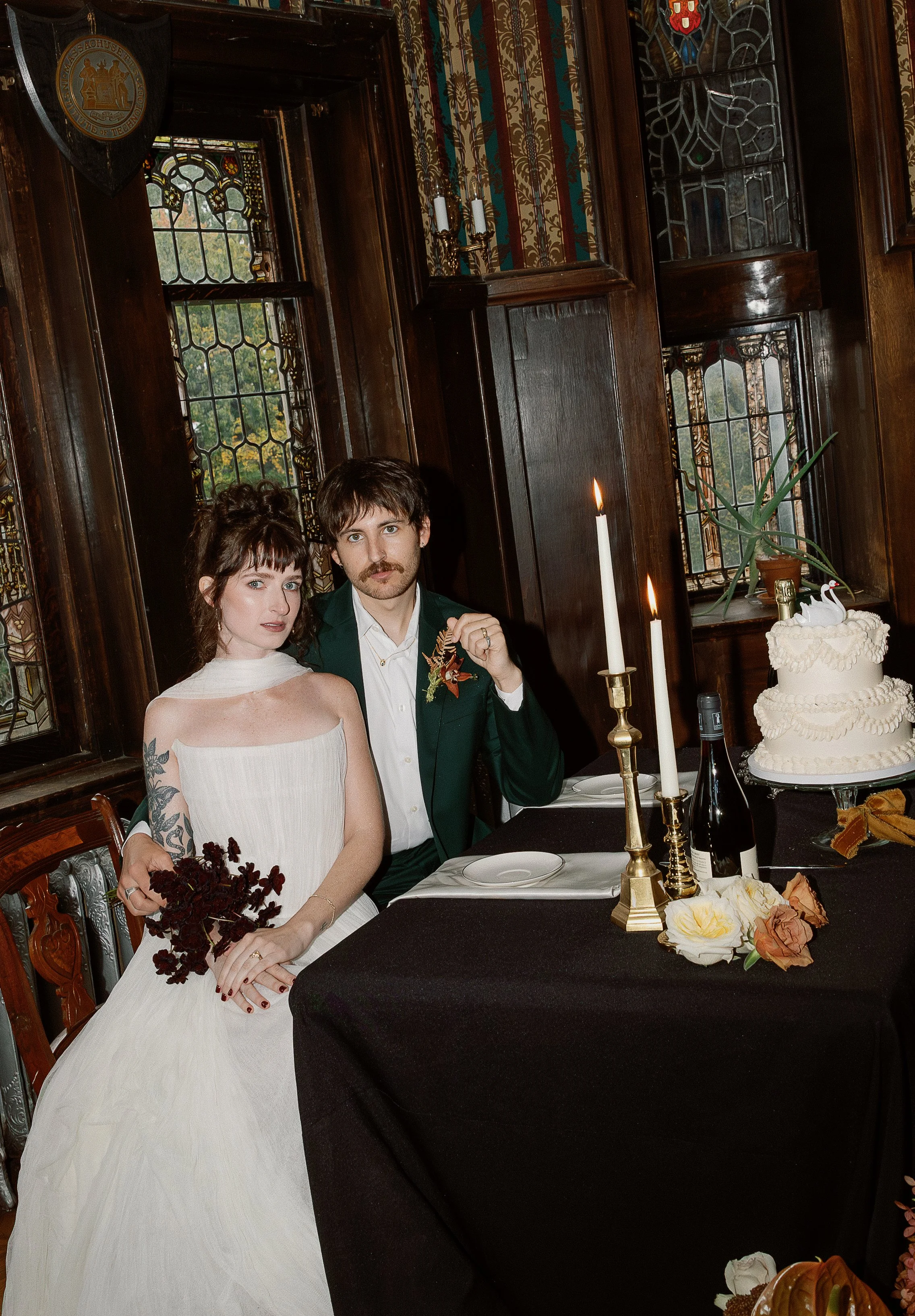 Moody shot of a couple on their wedding day sitting by their cake