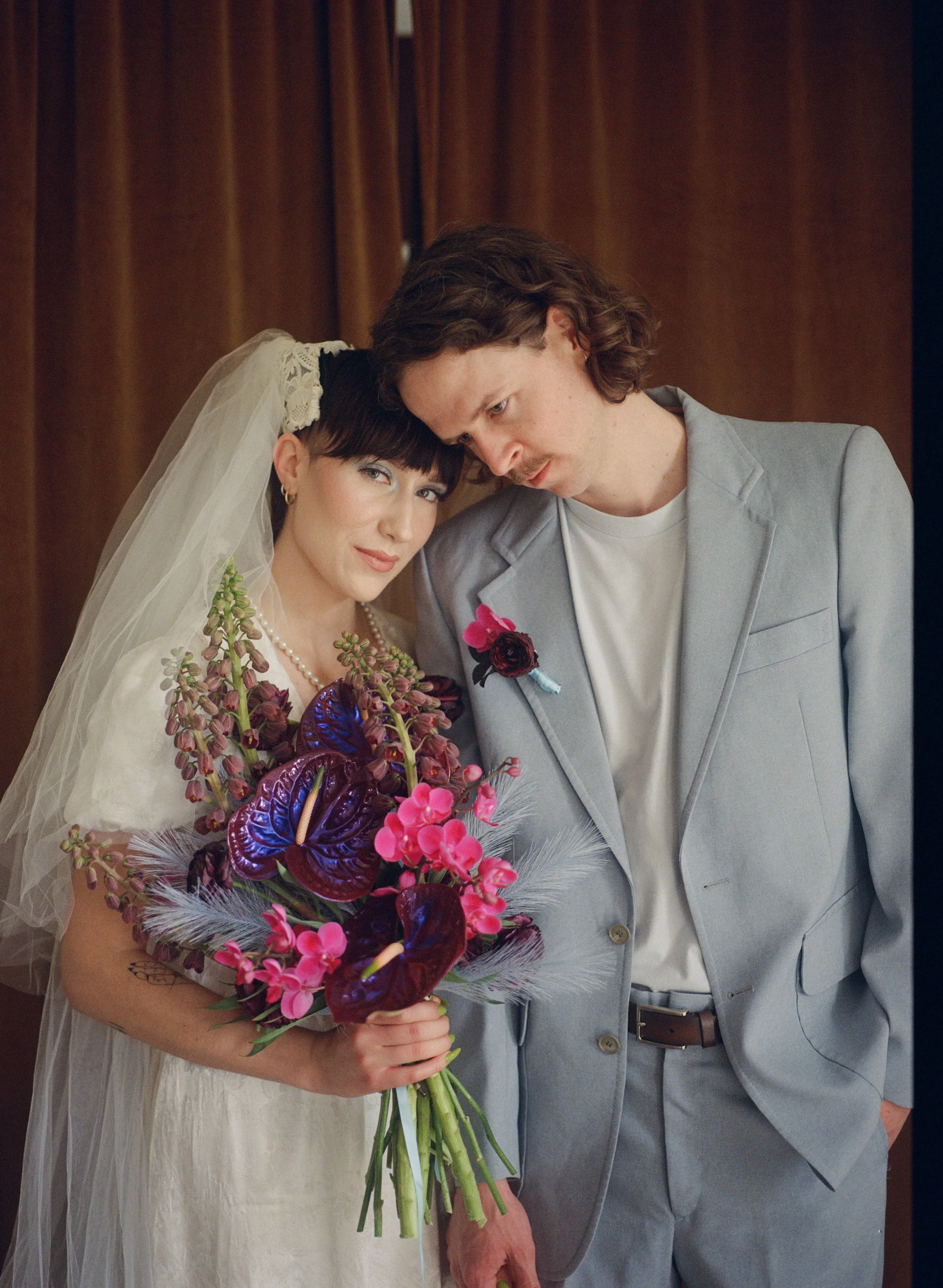 Husband and Wife on their wedding day holding bright, bold flowers