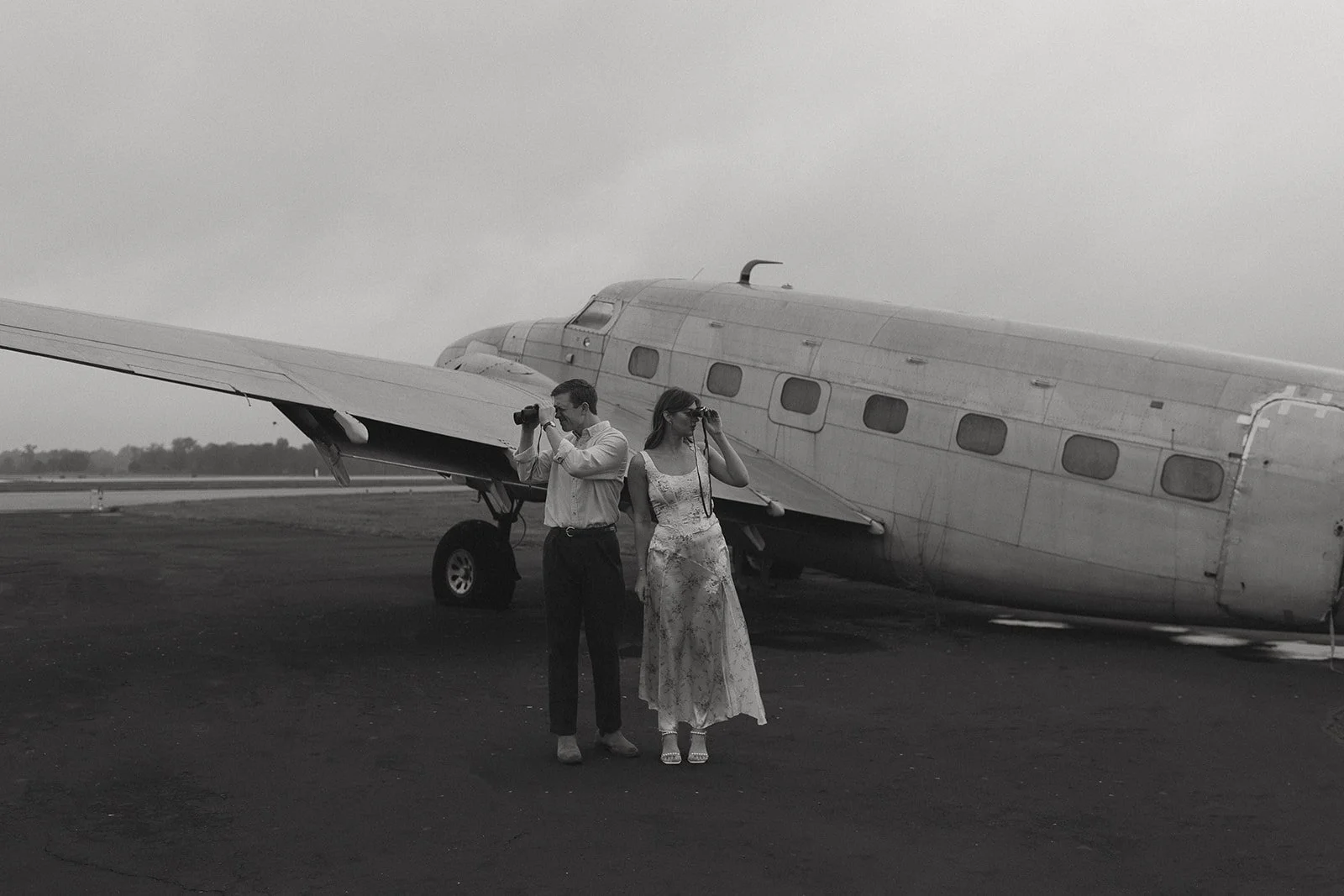 Couple standing in front of an airplane with binoculars