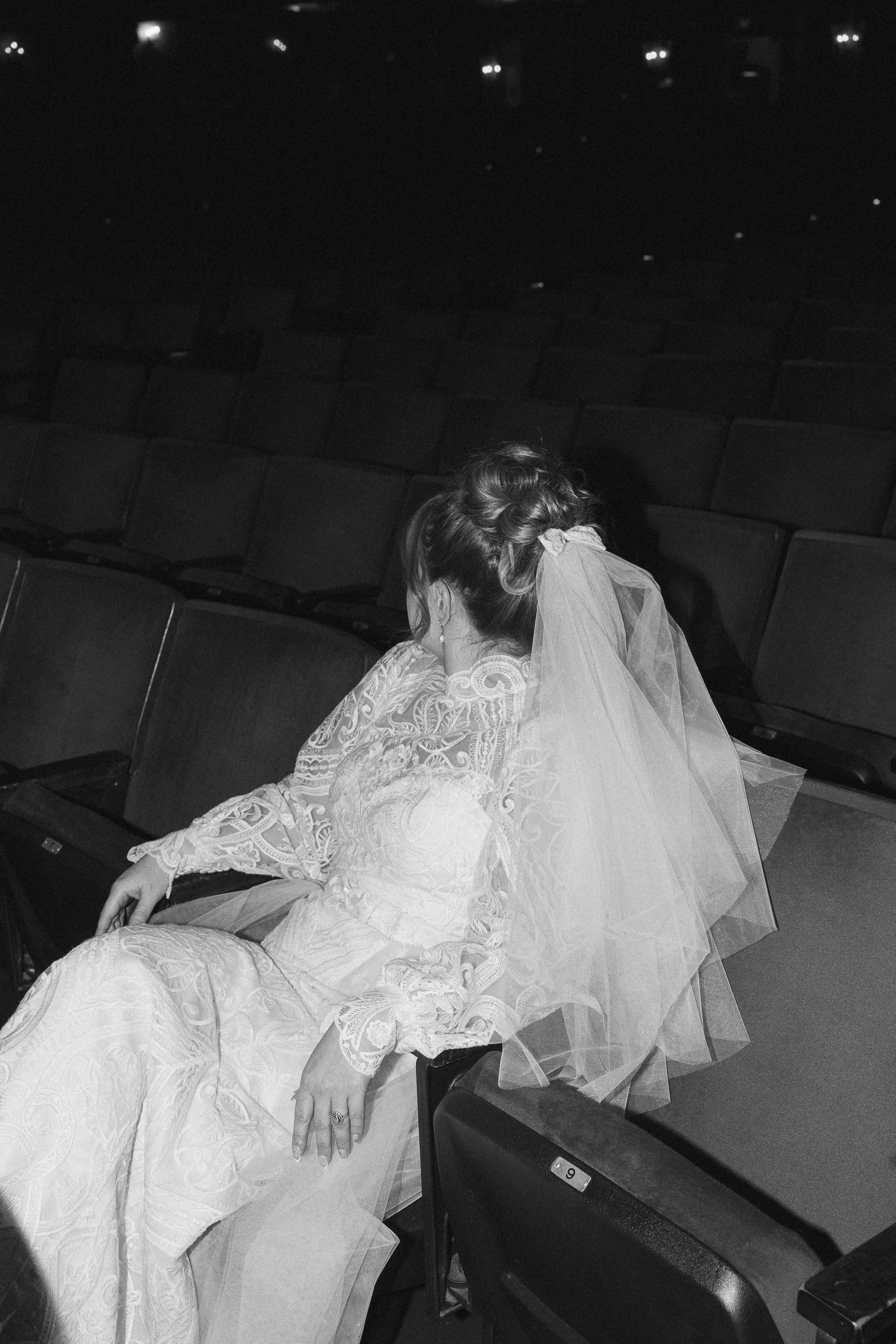 Black and shot shot of a bride sitting in a moody theatre