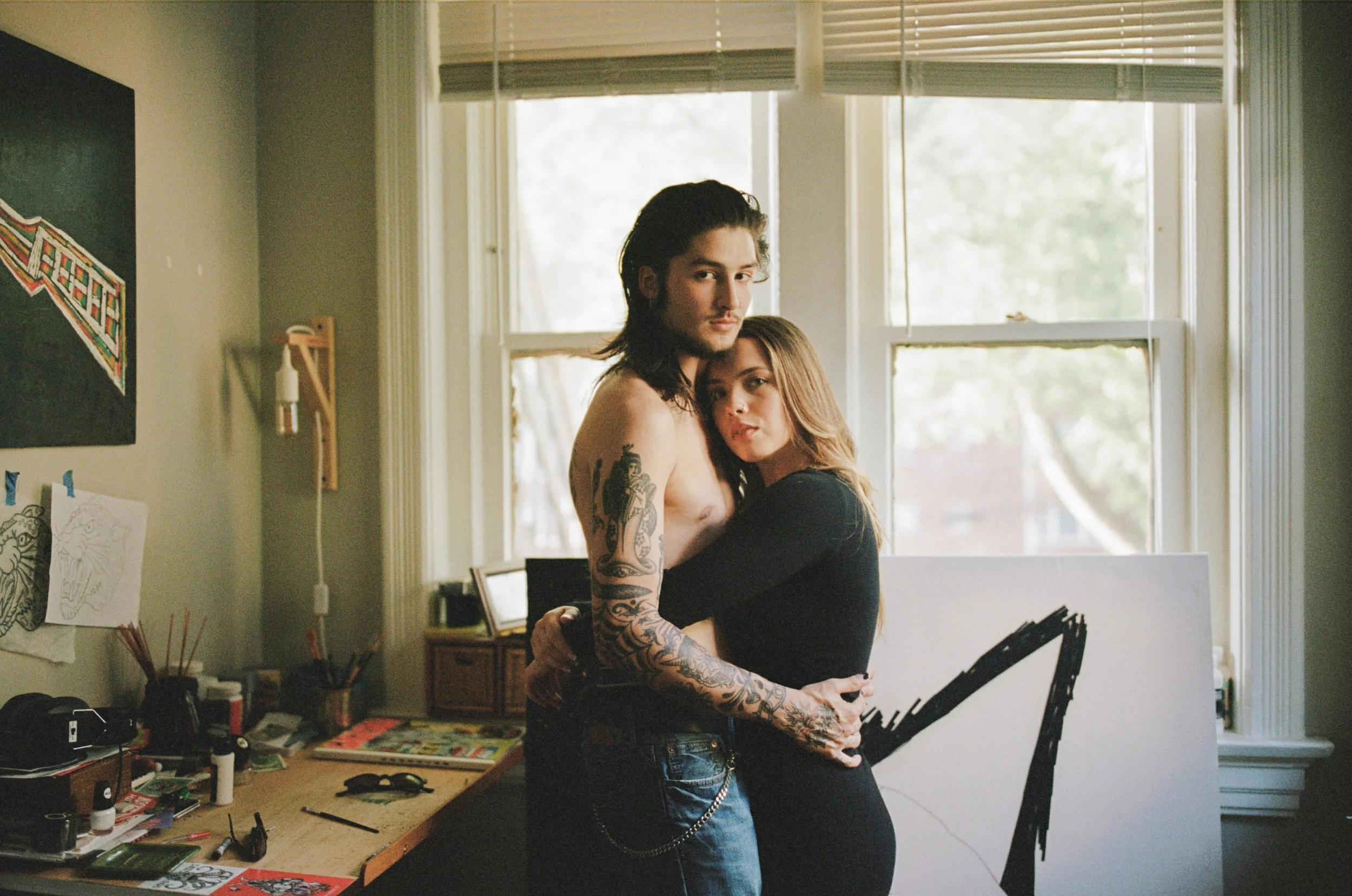 Intimate couple portrait standing in their home hugging and looking at the camera