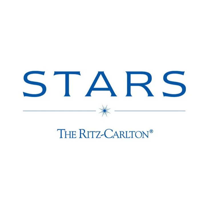 Logo for STARS at The Ritz-Carlton featuring a starburst graphic and blue text on a white background.