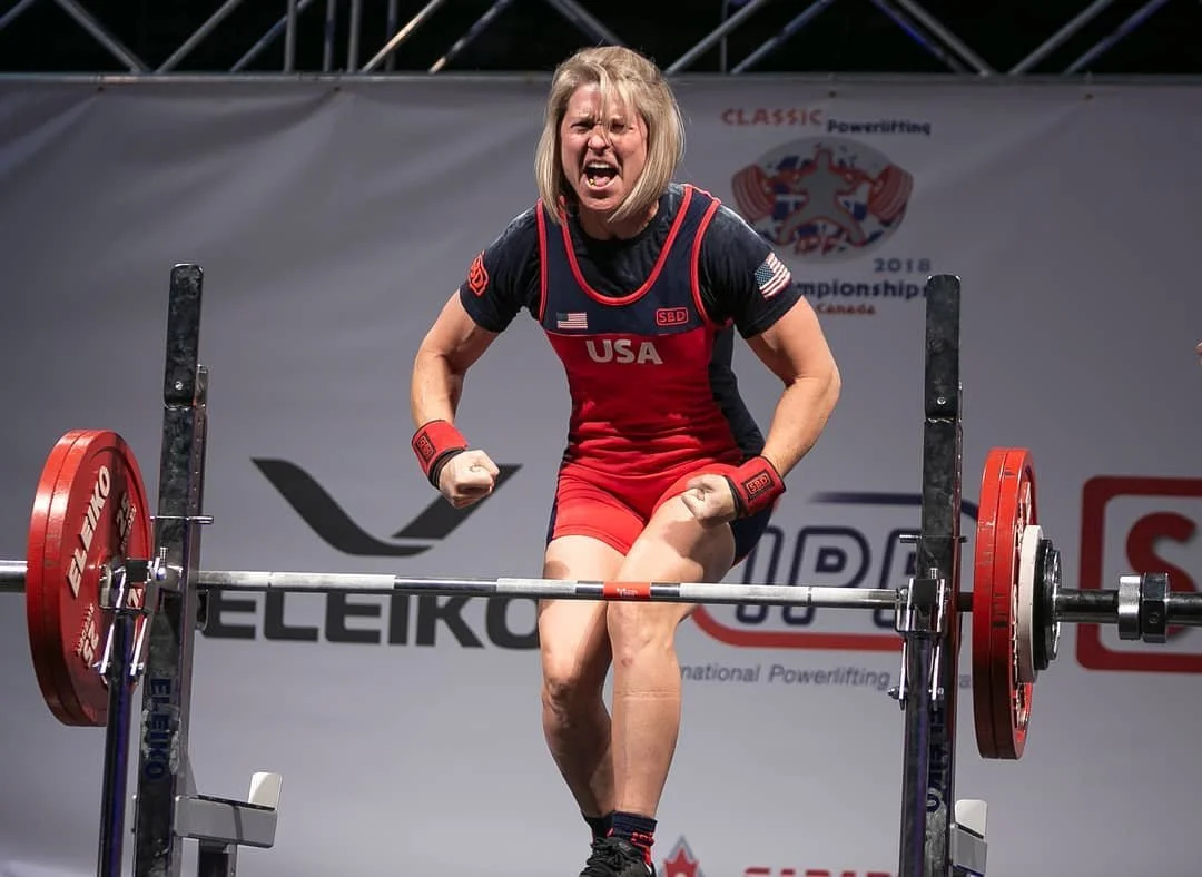 World record powerlifter Jen Thompson celebrates in front of a barbell