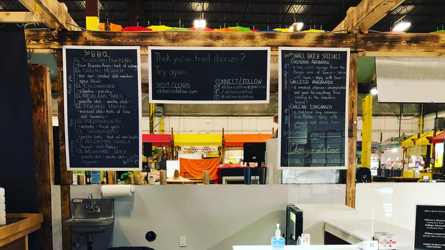Remote buildings on a hilltop with a snow-capped mountain range in the background under an overcast sky.
