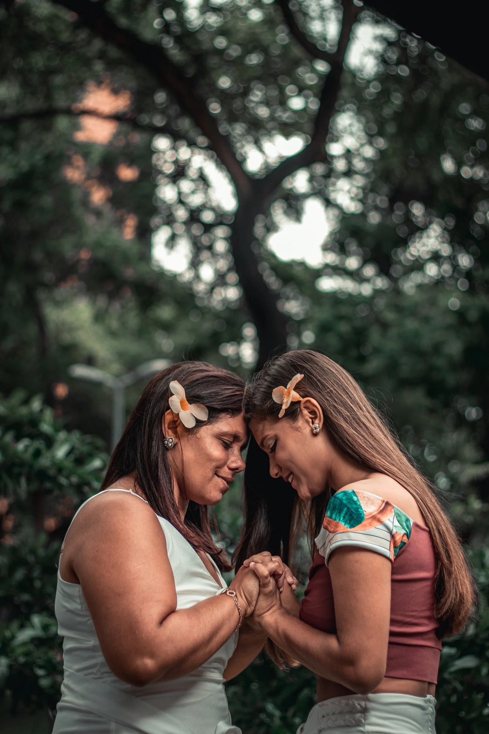 A close up of a mother linking hands with her teen daughter. Learn how teen counseling in San Diego, CA can offer support by searching for “anxiety in teens in San Diego” or “in-person therapy in San Diego” today.