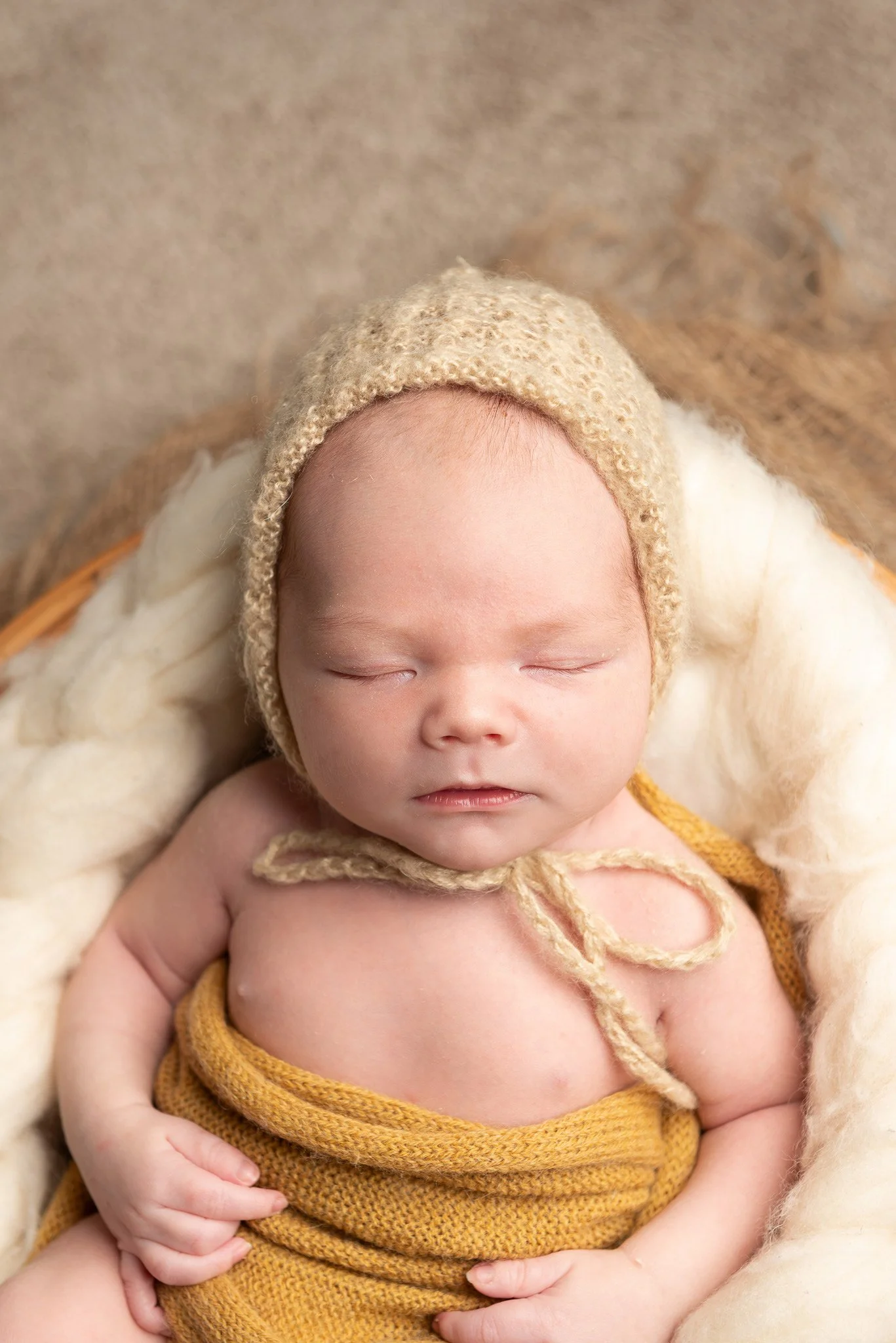 Keltaiseen vilttiin kiedottu vauva nukkuu vaalea myssy päässään.