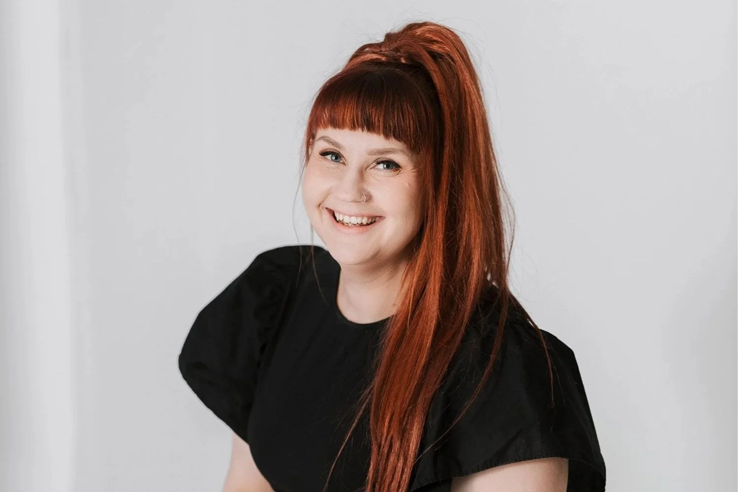 Maarit Lahikainen hymyilee valkoisen taustan edessä.