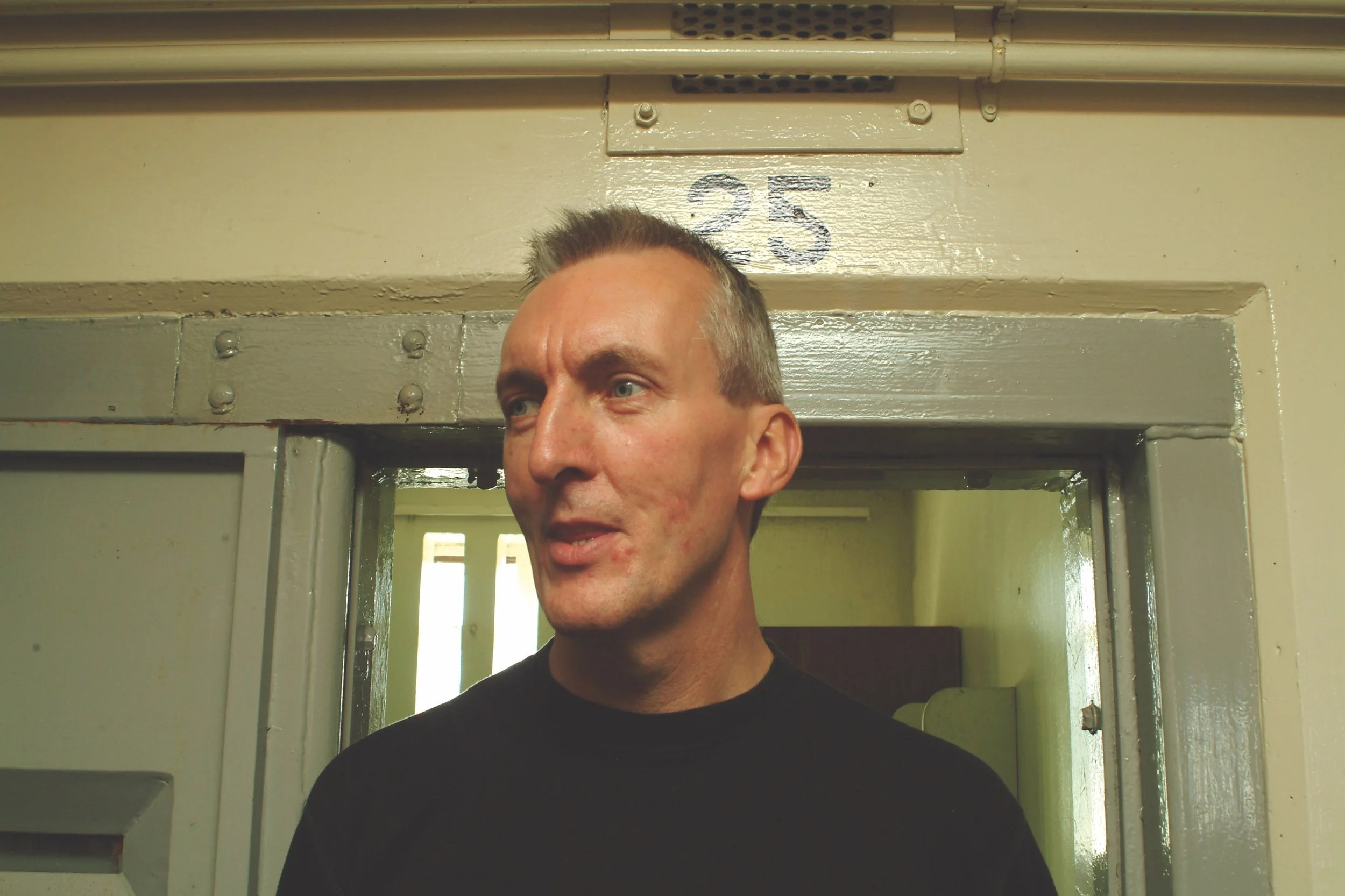 Man standing in front of a door with the number 25 above it