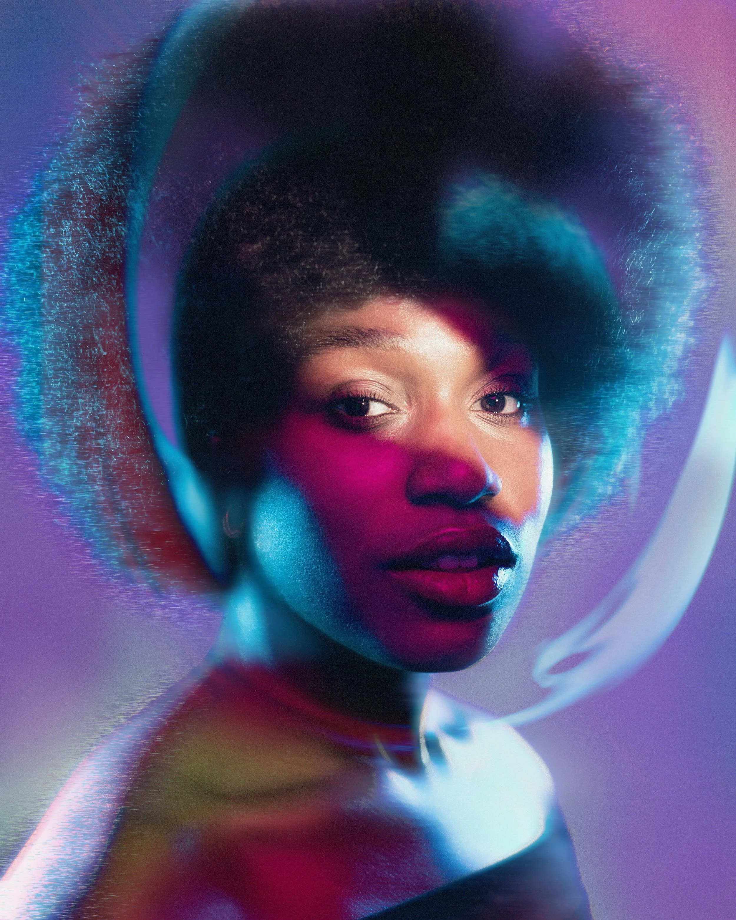 A portrait of a woman with an Afro hairstyle illuminated by vibrant pink, blue, and purple neon lighting, with a circular glass or plastic or acrylic element reflecting her face.