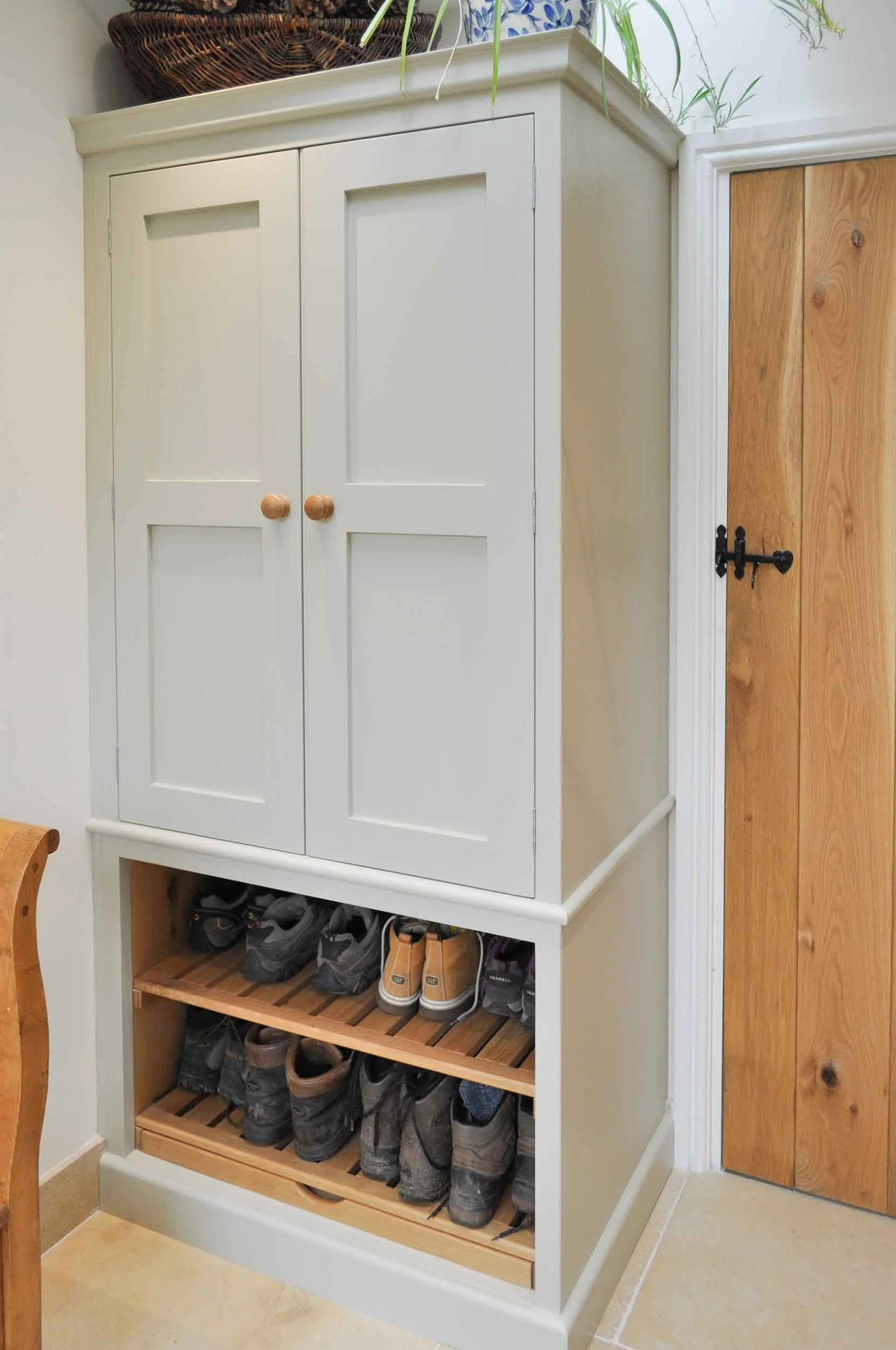 A bootroom cupboard with slatted shelves for shoes and pull-out dust tray beneath