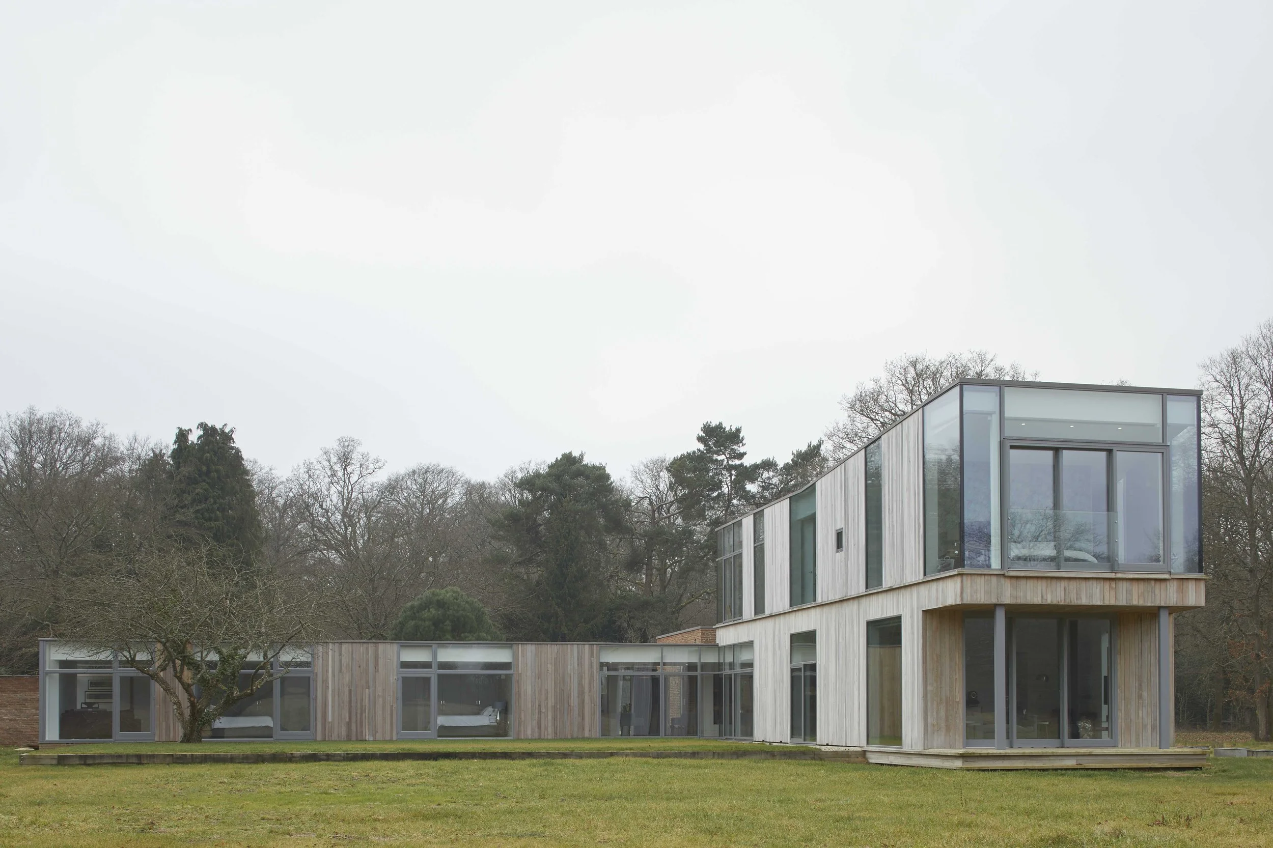 Set gently within its surroundings, this contemporary home is defined by clean geometry, natural materials, and expansive glazing. The building’s form responds to the landscape, creating a strong yet understated presence that prioritises light, outlo
