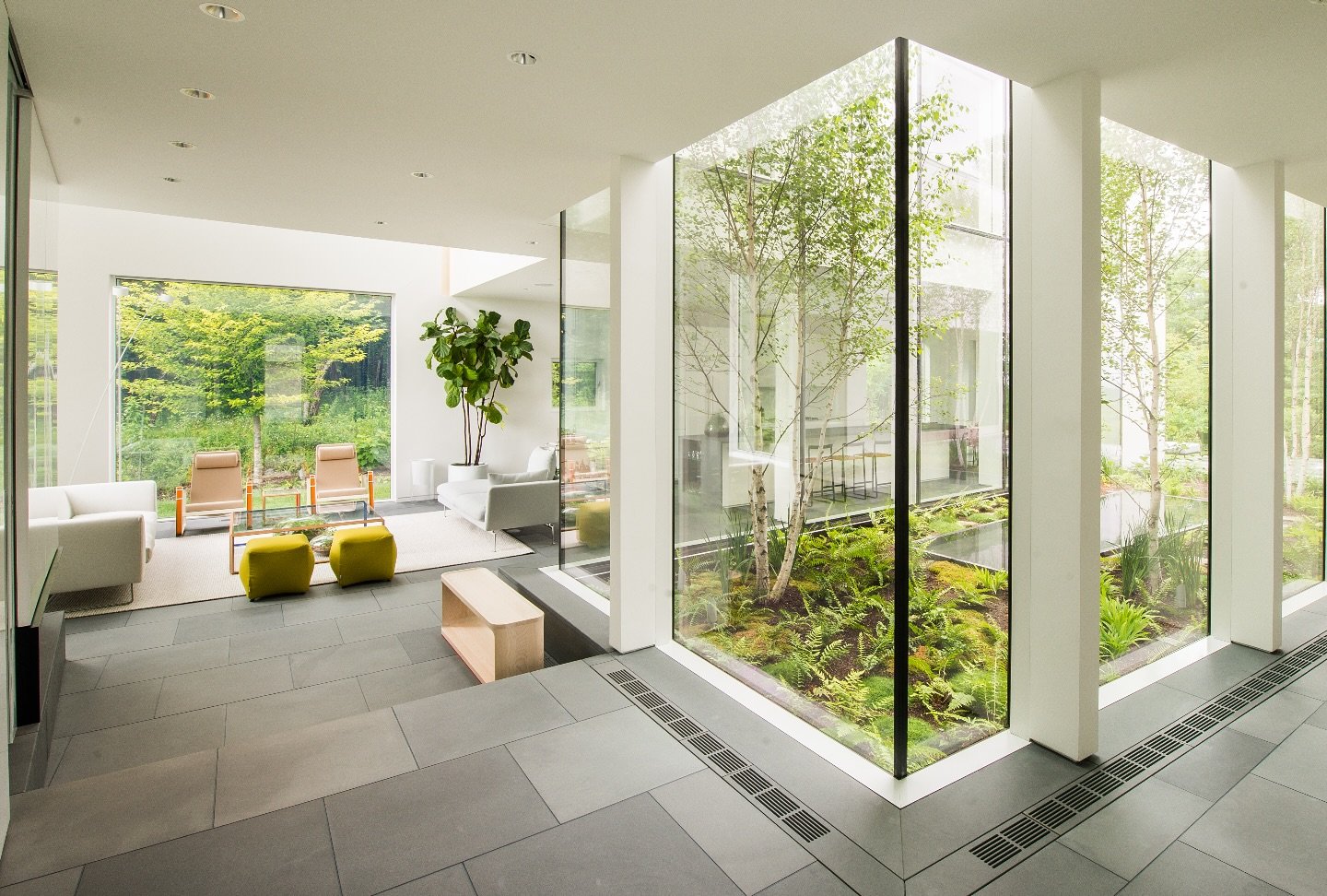 We love an impactful foyer. 
At our Hudson River Valley House project the front door opens to a view of the internal courtyard landscaped with birch, ferns, moss, and a dark granite reflecting pool. Directly ahead, the open, double-height living room