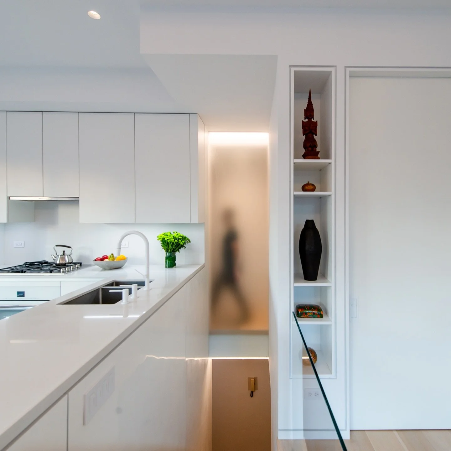 In this duplex gut renovation, an etched glass wall above the stair allows daylight to enter deep into the interior, while making circulation visible.

The monochromatic white kitchen amplifies luminosity and its color belies the durability of its fu