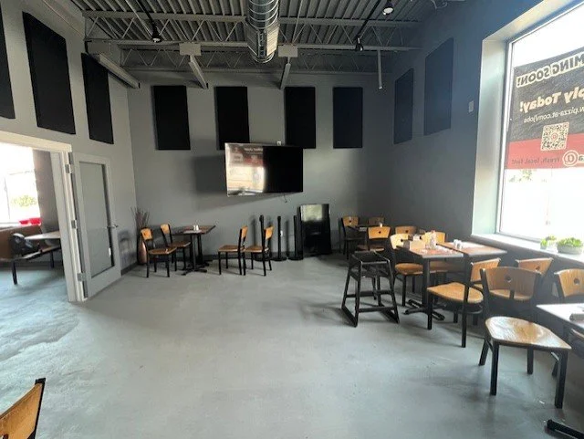 Seating area with grey walls and wood and metal chairs and tables.