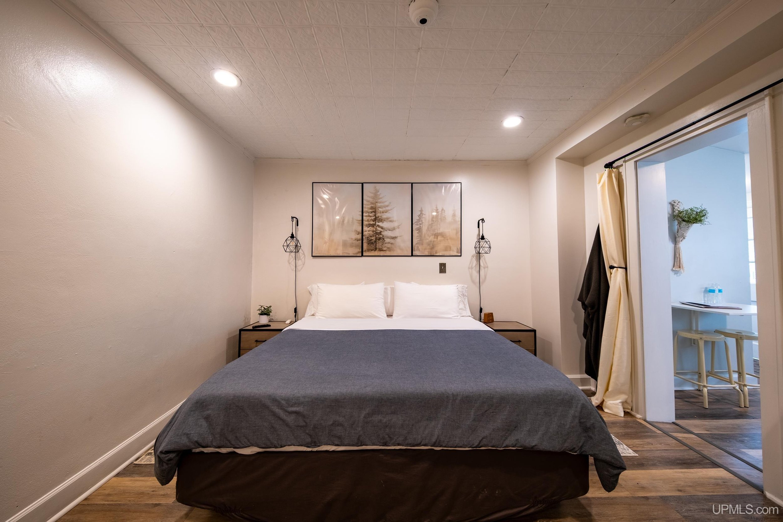 A bed in an apartment with a living area to the right.