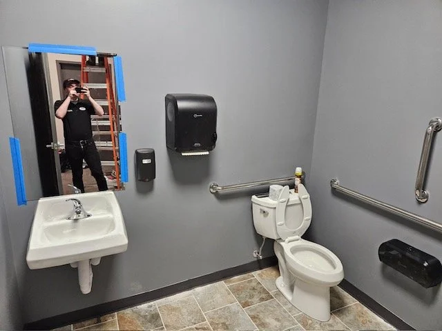 Bathroom with grey walls, toilet on the left and sink and mirror on the right.