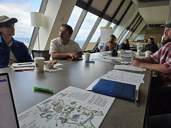 People sit and talk in a conference room with colorful papers.