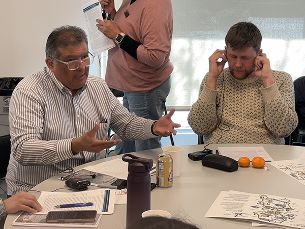 Two people at a table with paperwork listen, speak, and collaborate at a workshop.