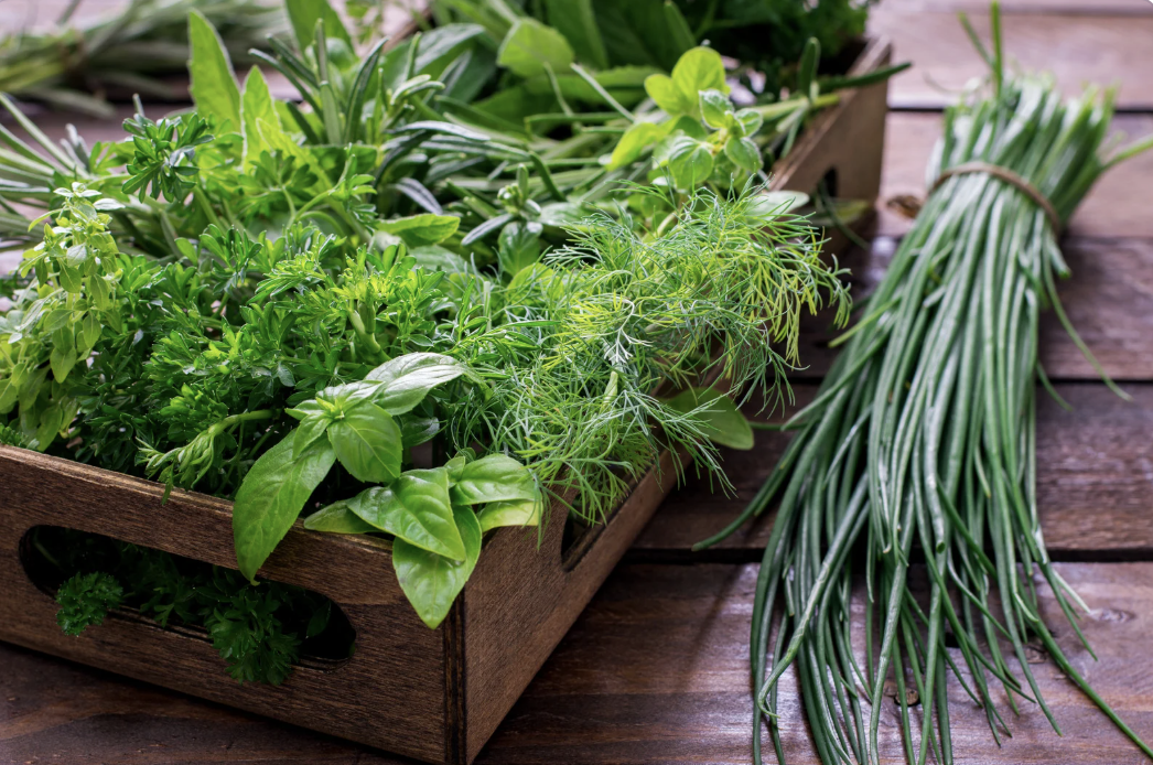wooden box of fresh herbs with chives on wooden table
