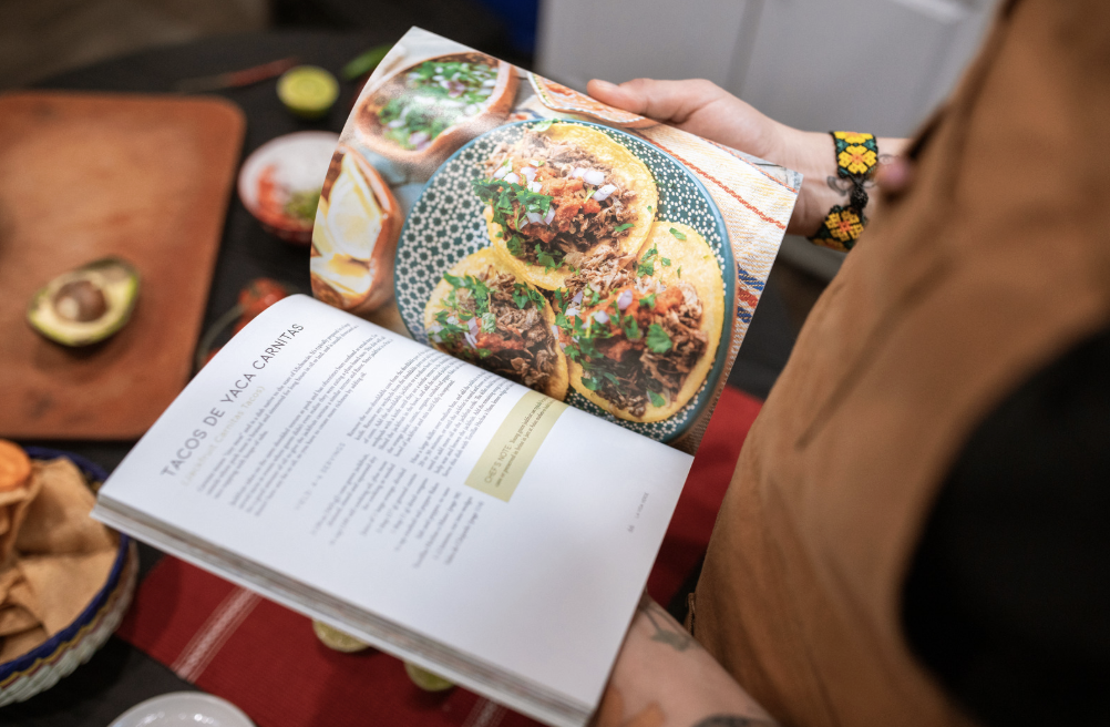 woman holding an open cookbook in her kitchen