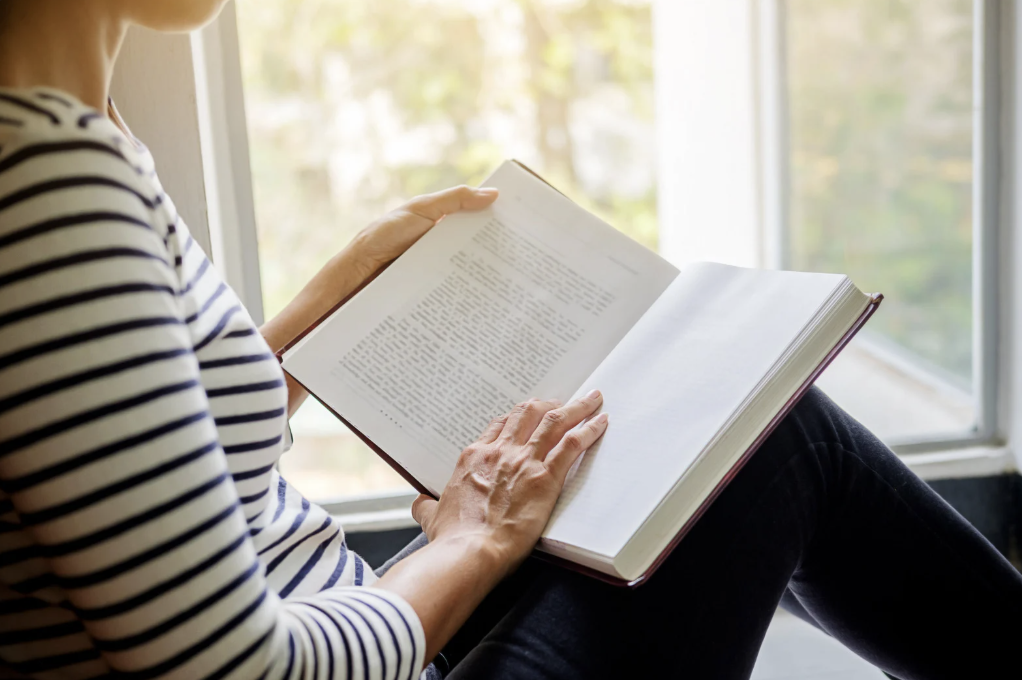 woman sitting in window seat reading a book