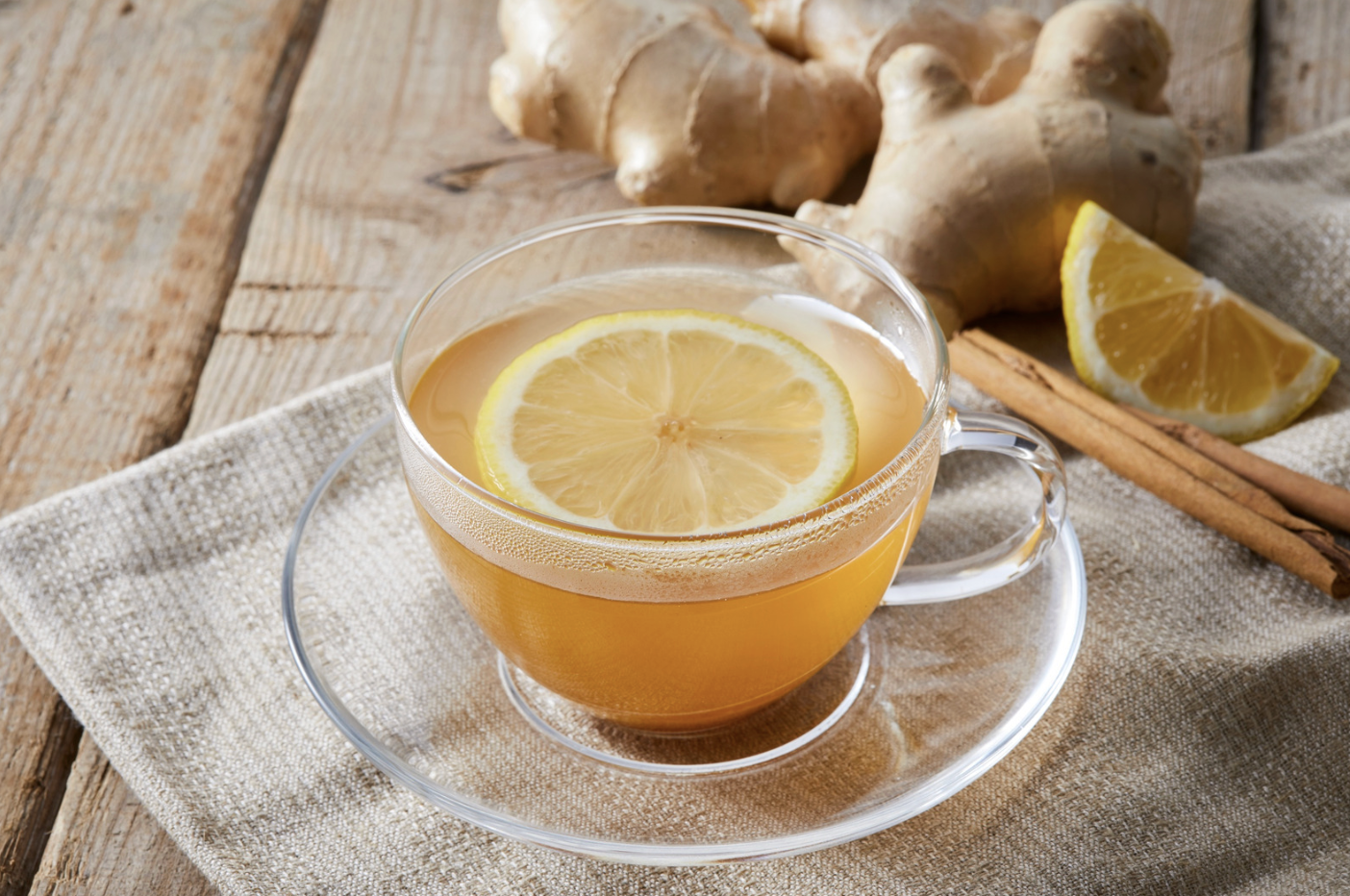 hot herbal tea in glass cup with ginger, cinnamon and lemon