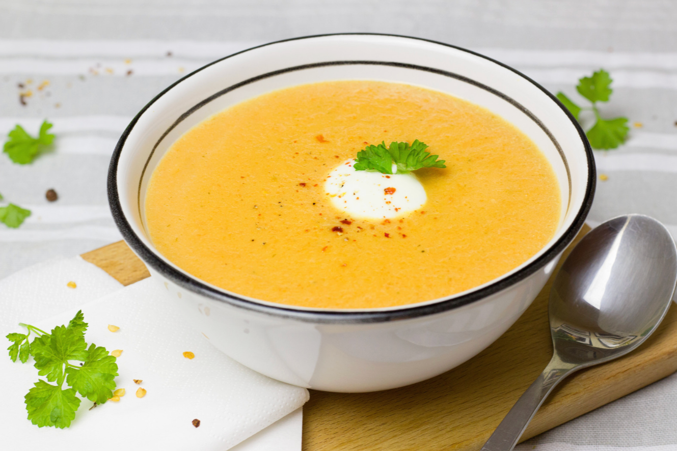 bowl of carror soup with fresh herbs