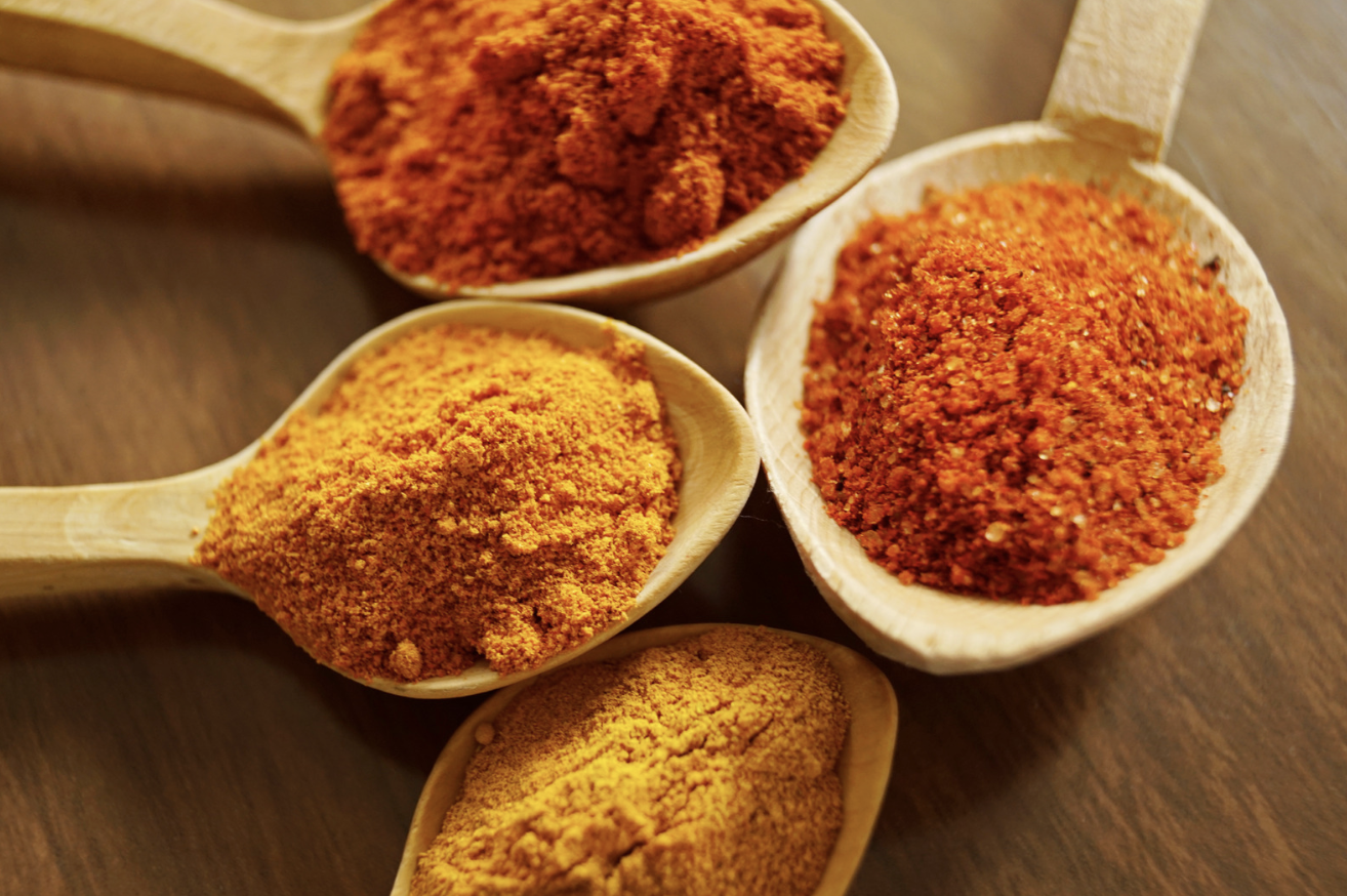 wooden spoons filled with ground spices