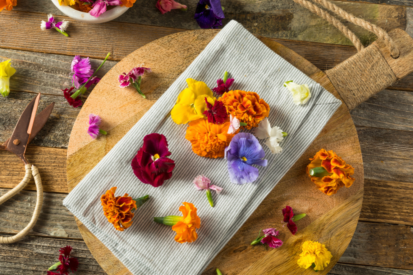 edible flower blossoms on striped towel placed on wooden cutting board