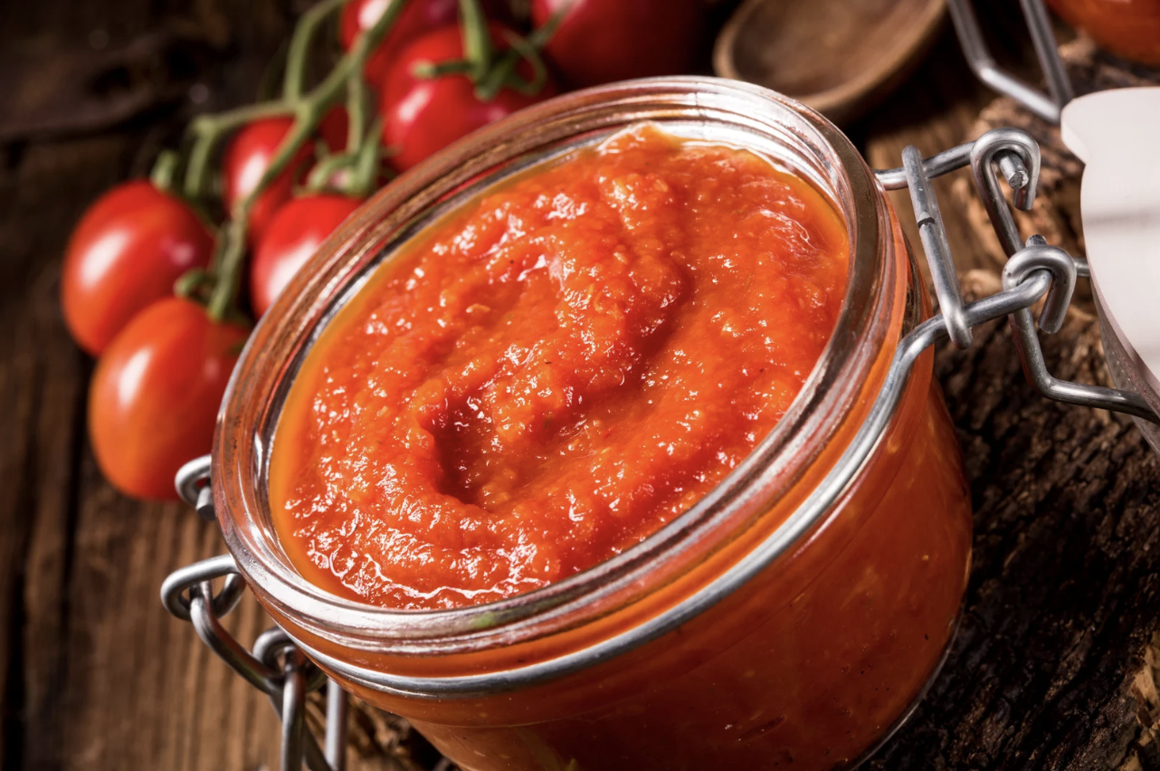 homemade tomato sauce in glass jar on wooden table