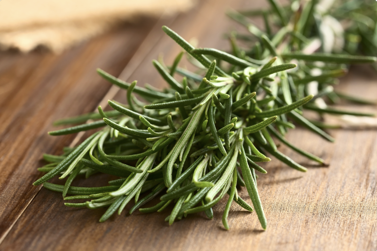 cut fresh rosemary laying on wooden table